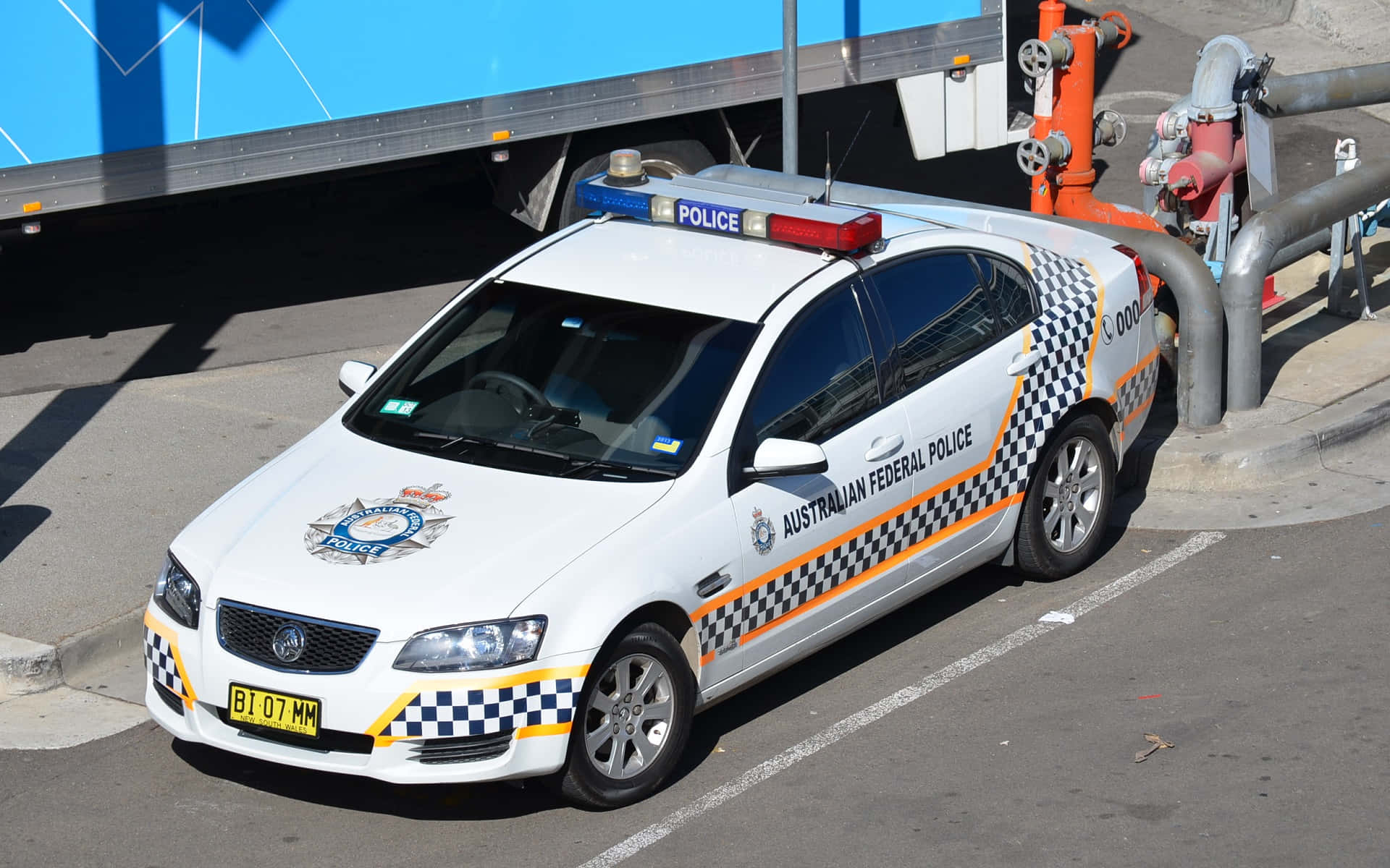 澳洲聯邦警車在晴朗日子停泊在貨車附近。