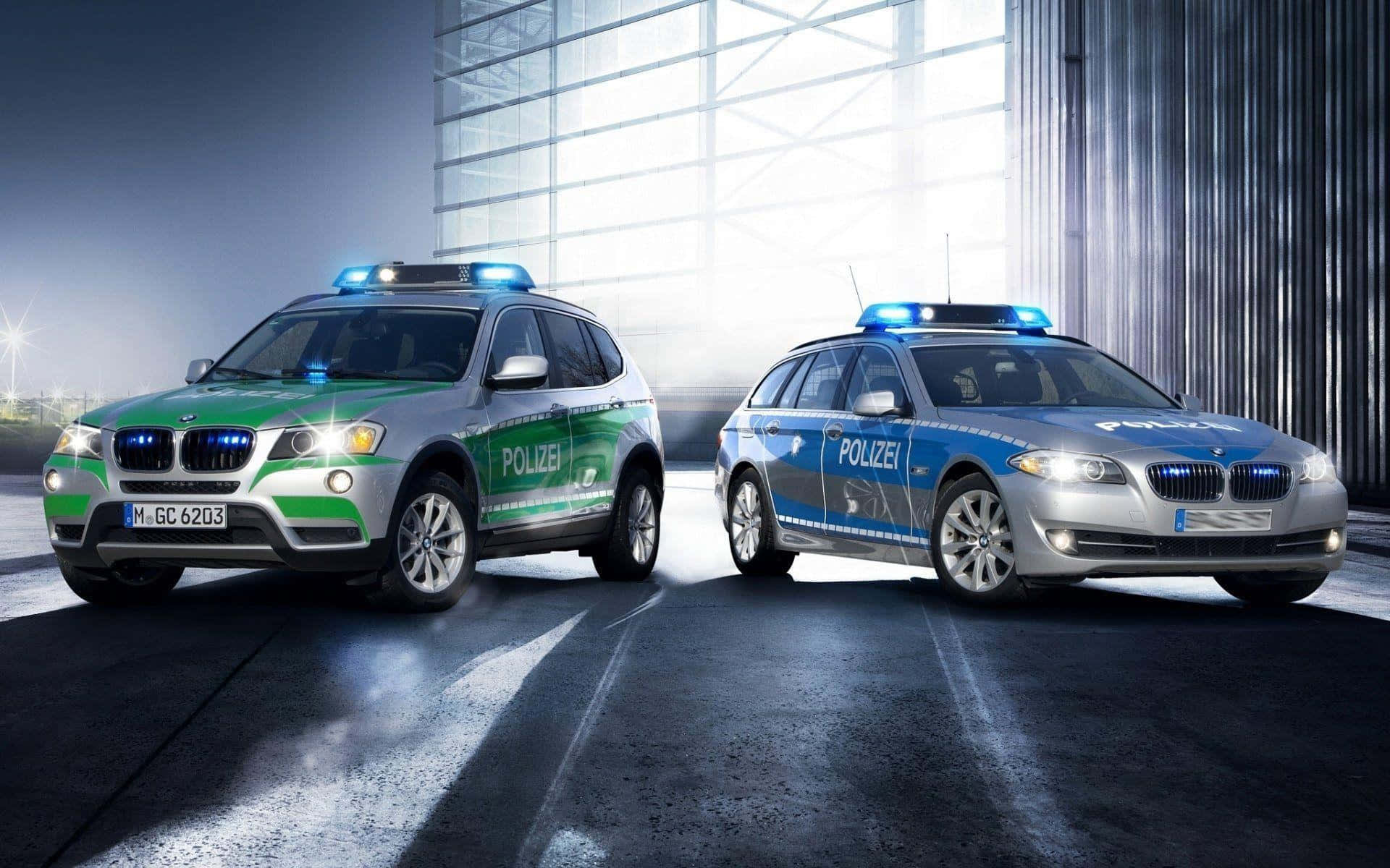 兩輛寶馬警車在夜間現代建築中停泊，閃爍著燈光。