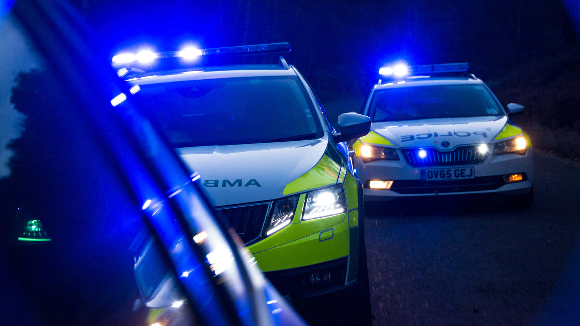 夜間黑暗道路上兩輛閃著藍燈的警車。