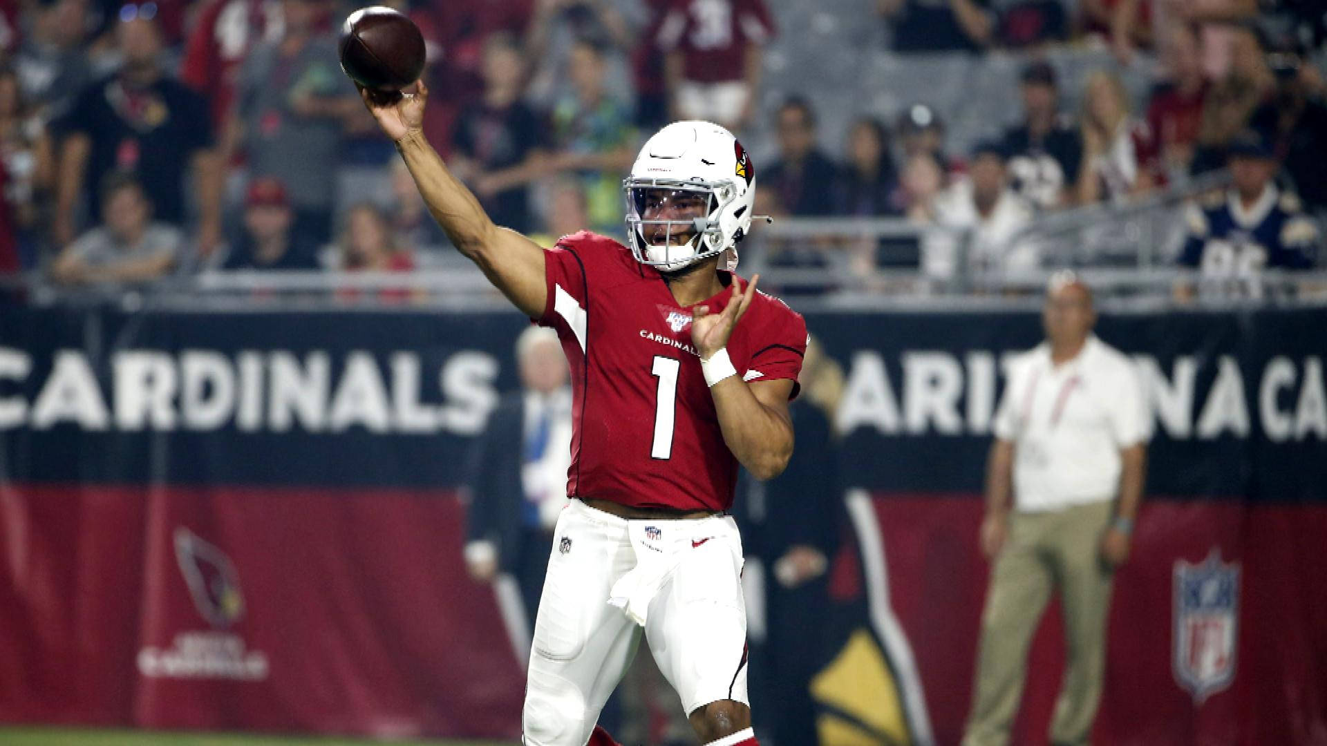 基奧勒·默里投球動作 壁紙 — 亞利桑那紅雀隊的四分衛身穿紅色1號球衣，在夜間比賽中於球場燈光下擲出橄欖球。