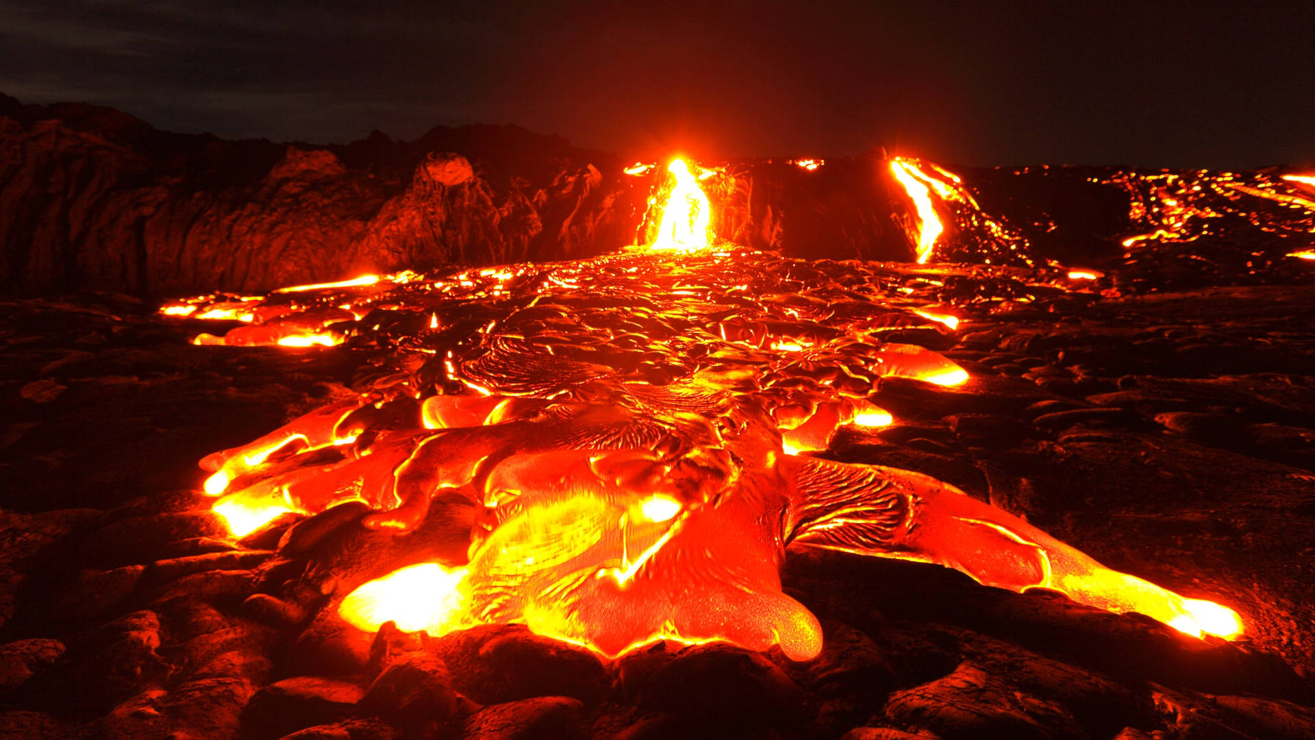 熔岩流和噴發在夜間照亮了黑暗的火山景觀。
