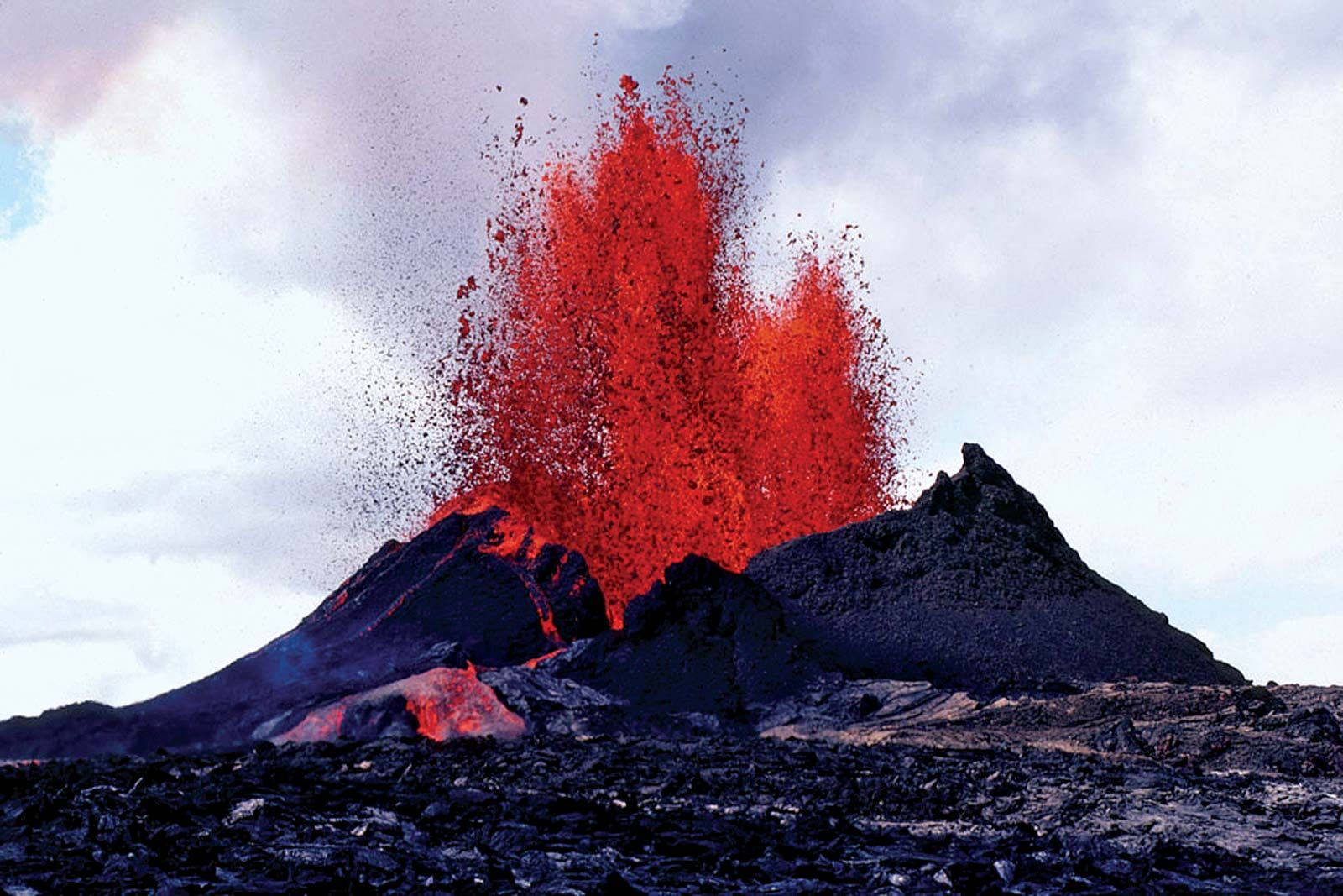 火山爆發，在陰天背景下噴出明亮的紅色熔岩。