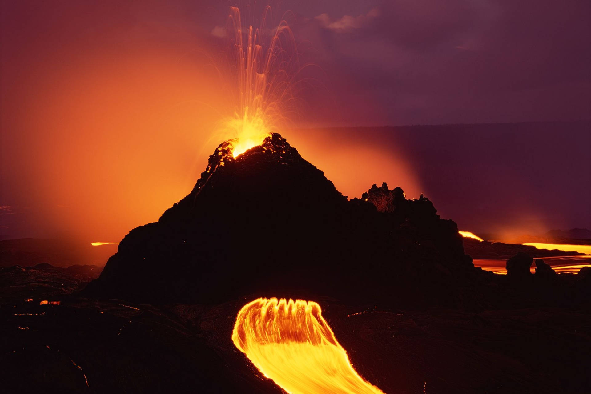 火山爆發，明亮的橙色熔岩噴泉和河流流入黑暗的景觀。
