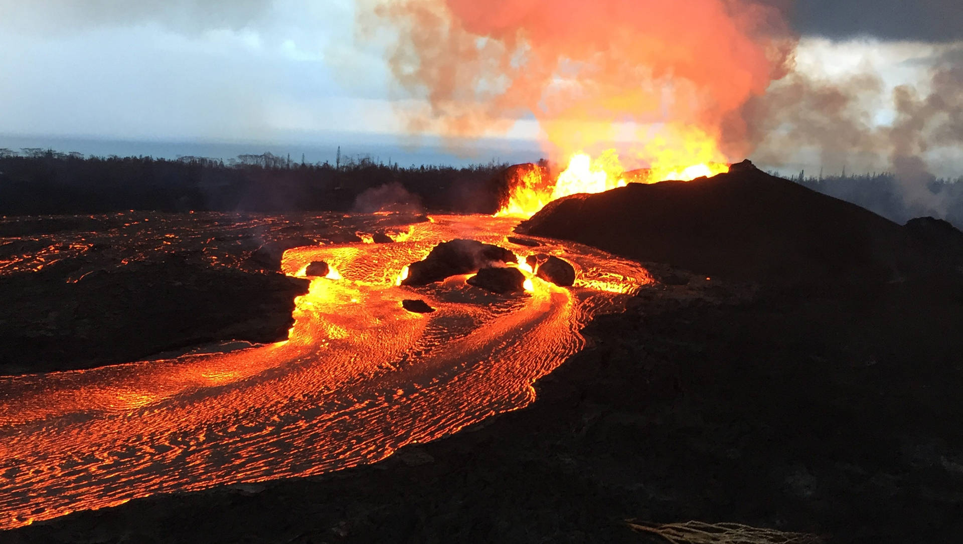 熔岩流發出橙色光芒，在黃昏時沿著黑暗的火山景觀傾瀉而下。