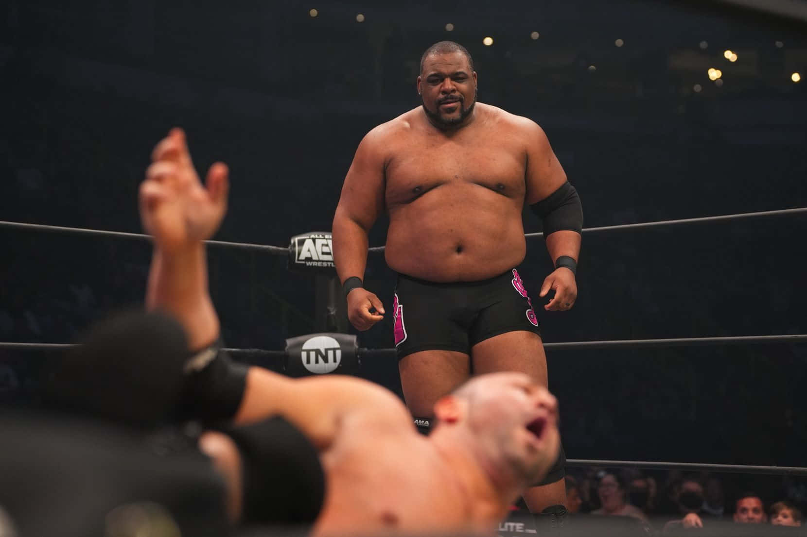 基斯·李與AEW的QT Marshall 壁紙 — 一位肌肉發達的摔角手在擂台上勝利地站著，而他的對手則被擊敗，雙臂高舉以示認輸。