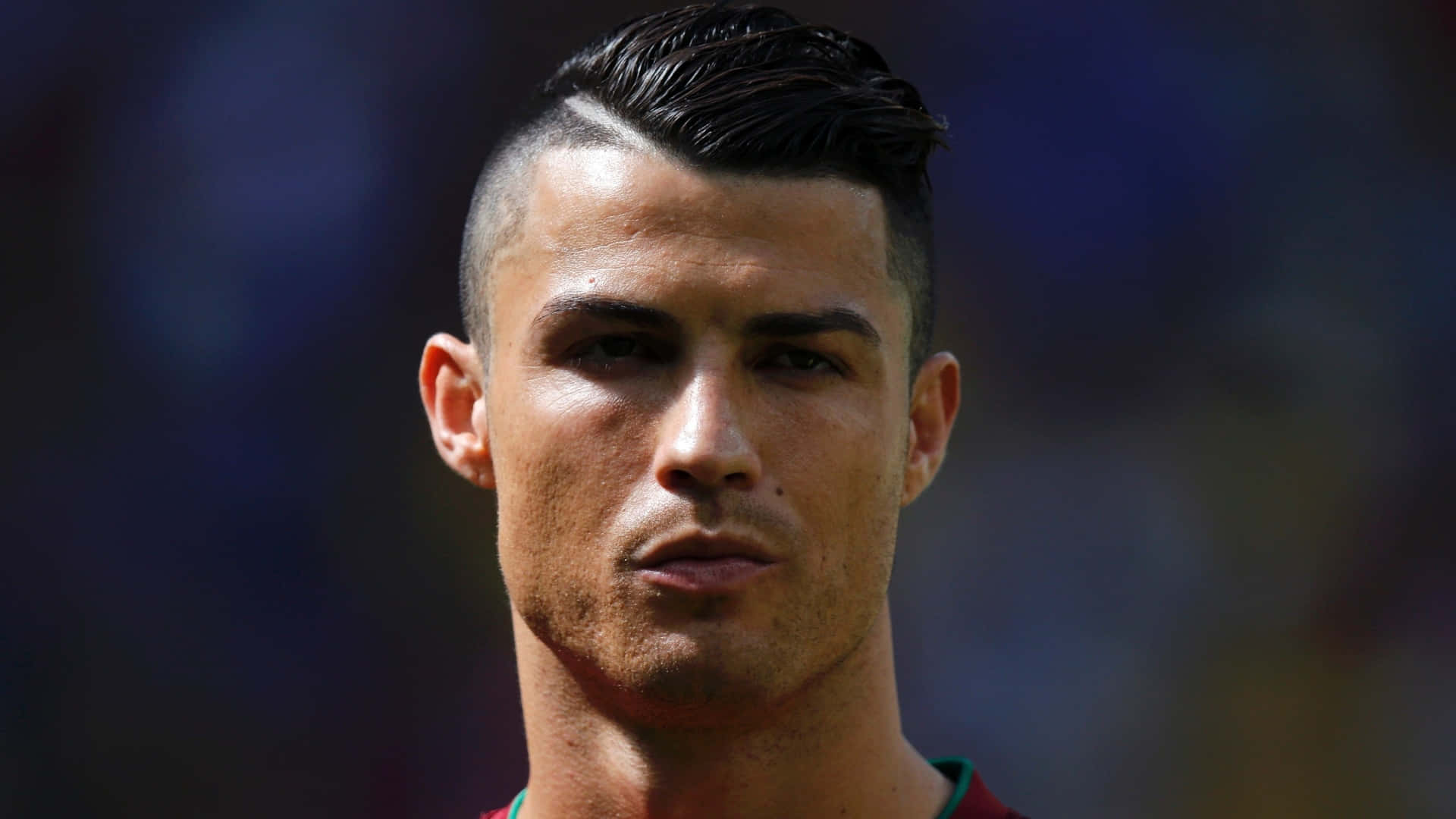 Ronaldo 桌布 壁紙 — 基斯坦奴·朗拿度嘅特寫肖像，帶有銳利嘅髮型同強烈嘅眼神，背景係模糊嘅球場。