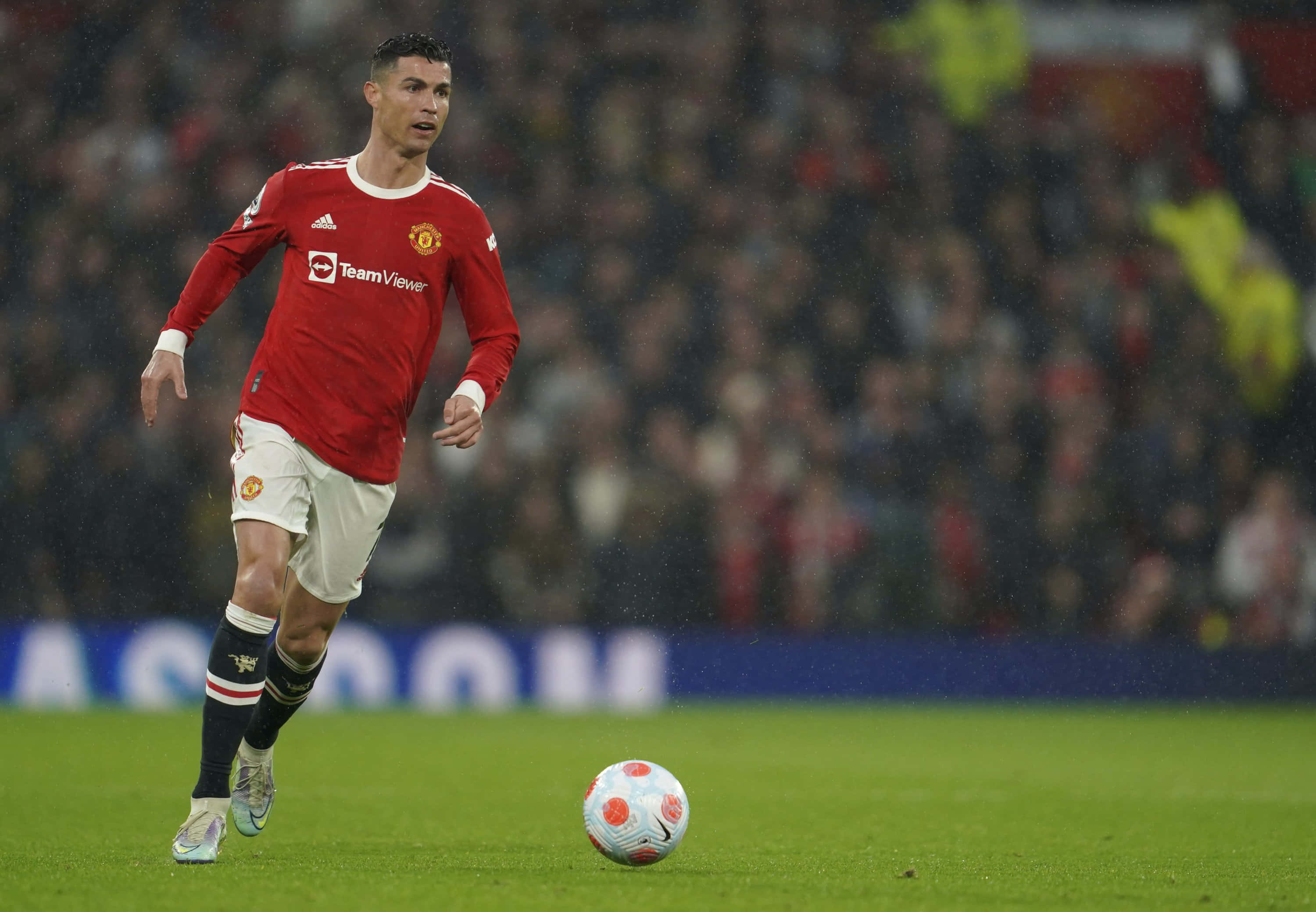 Cristiano Ronaldo 桌布 壁紙 — 基斯坦奴·朗拿度在球場燈光下於濕滑的草地上盤球，背景有模糊的球迷。