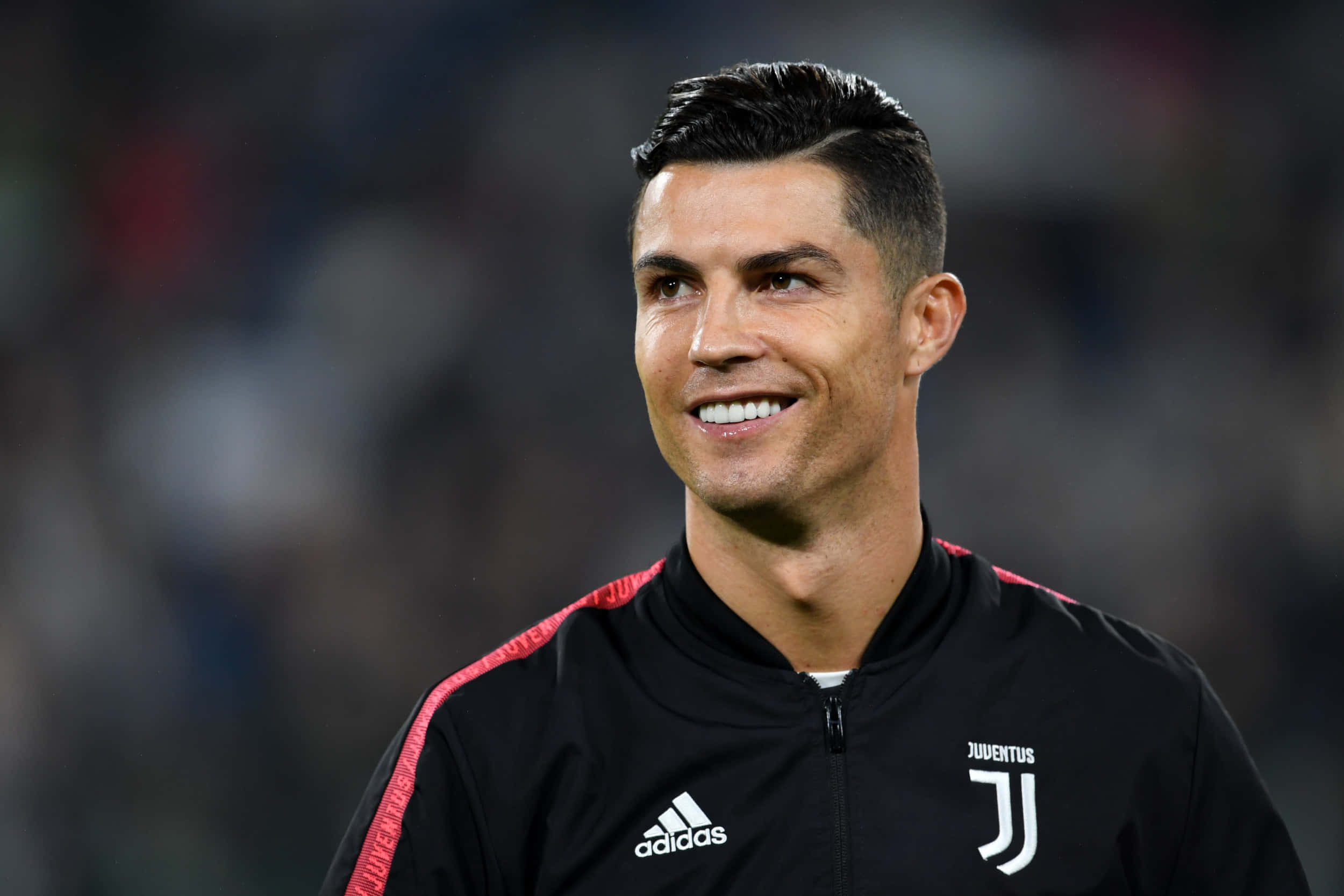 Ronaldo 桌布 壁紙 — 基斯坦奴·朗拿度在球場燈光下穿著黑色祖雲達斯訓練外套自信地微笑。