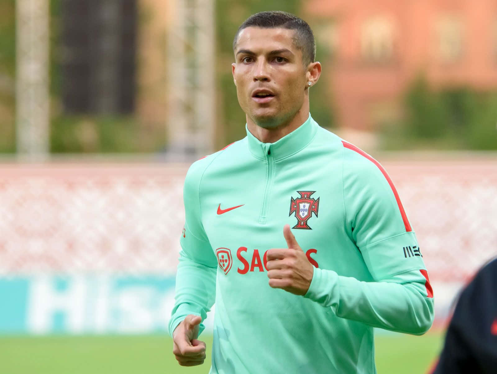 Cristiano Ronaldo 桌布 壁紙 — 基斯坦奴·朗拿度身穿淺綠色葡萄牙訓練球衣，在草地場上豎起大拇指，背景為模糊的球場。