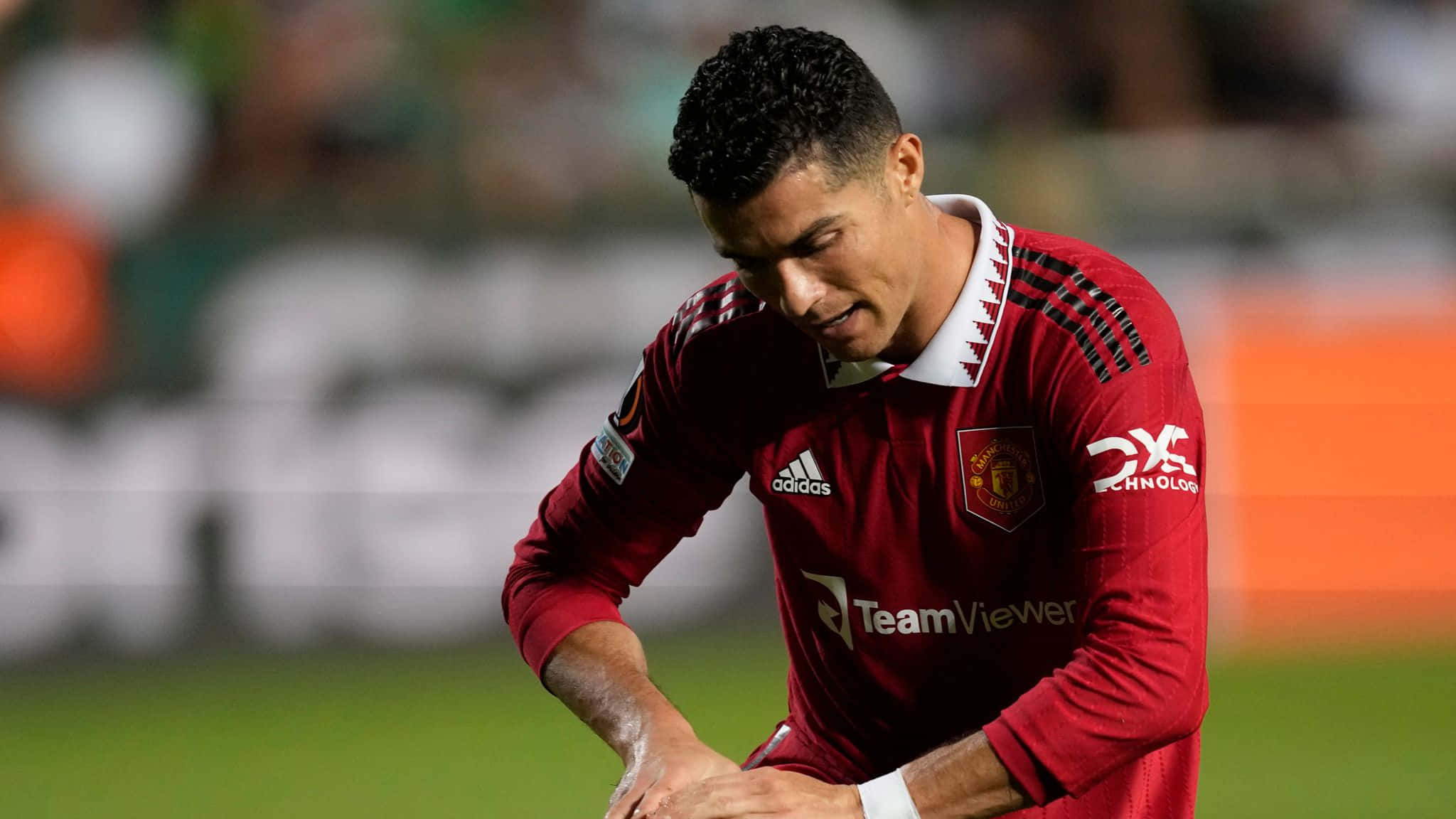 Cristiano Ronaldo 桌布 壁紙 — 基斯坦奴·朗拿度身穿紅色曼聯球衣，在球場燈光下專注地低頭看著綠色足球場。