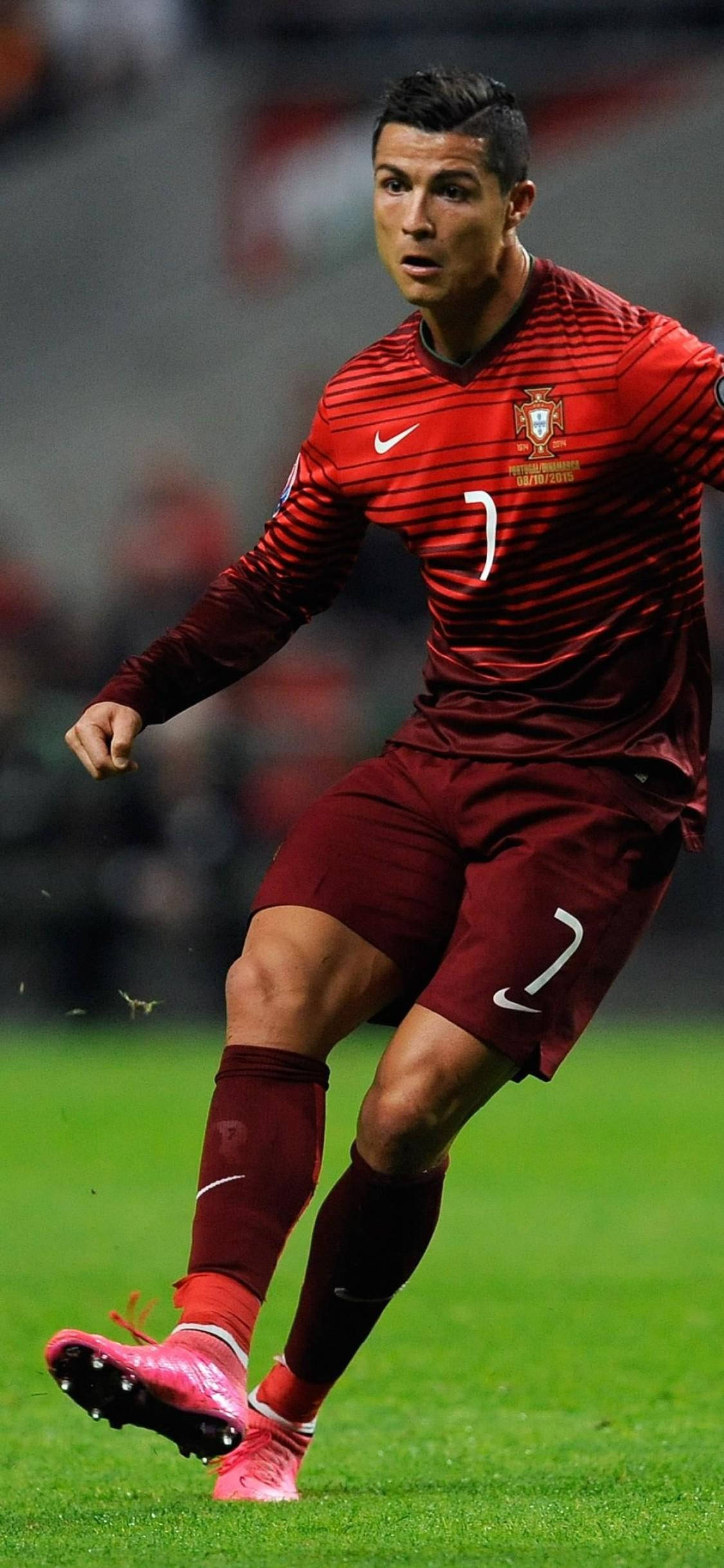 Cristiano Ronaldo 桌布 壁紙 — 基斯坦奴·朗拿度身穿紅色葡萄牙球衣，在球場燈光下於充滿活力的綠色草地上盤球。