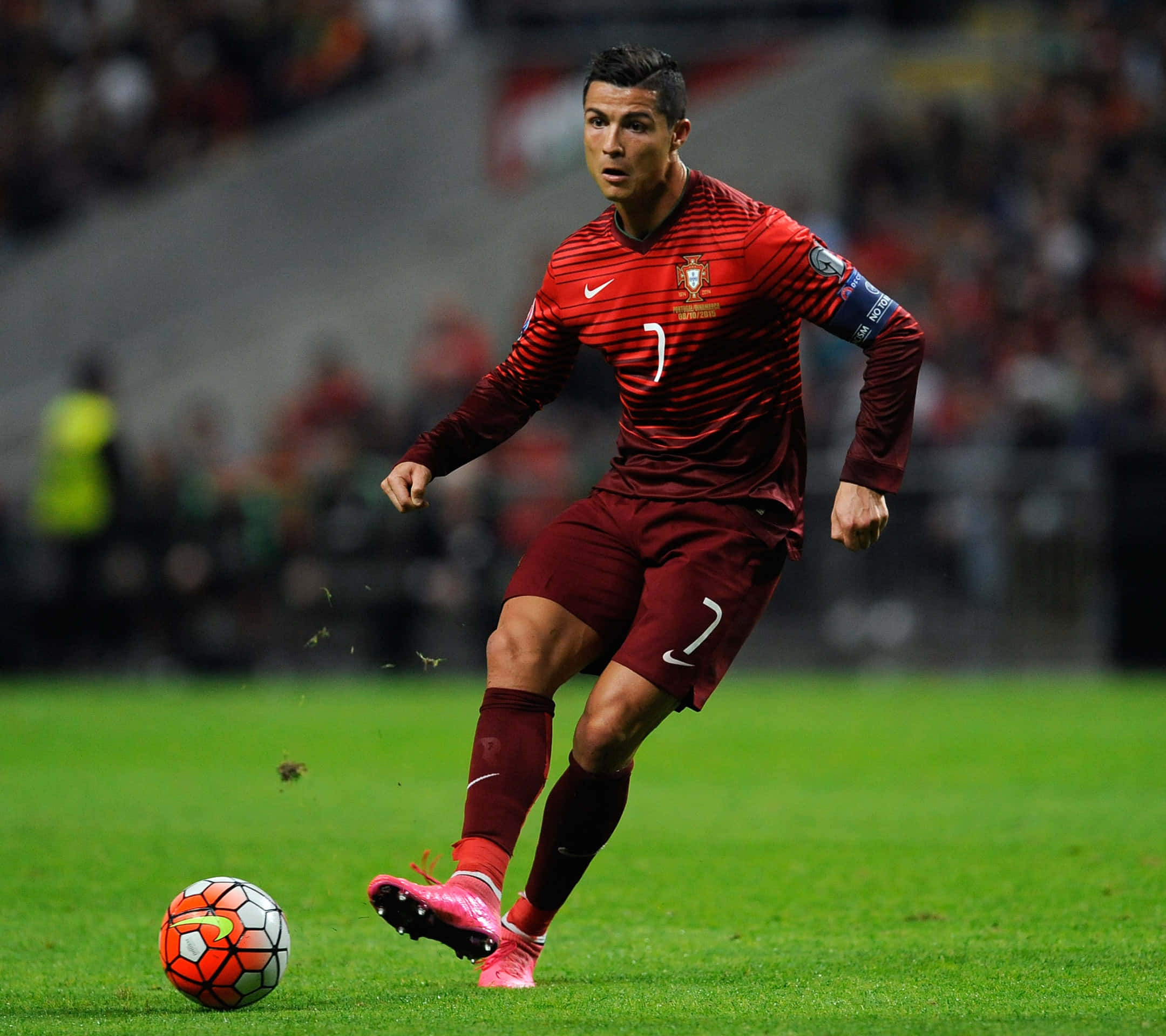Ronaldo 桌布 壁紙 — 基斯坦奴·朗拿度身穿紅色葡萄牙球衣，在球場燈光下於充滿活力的綠色草地上盤球。