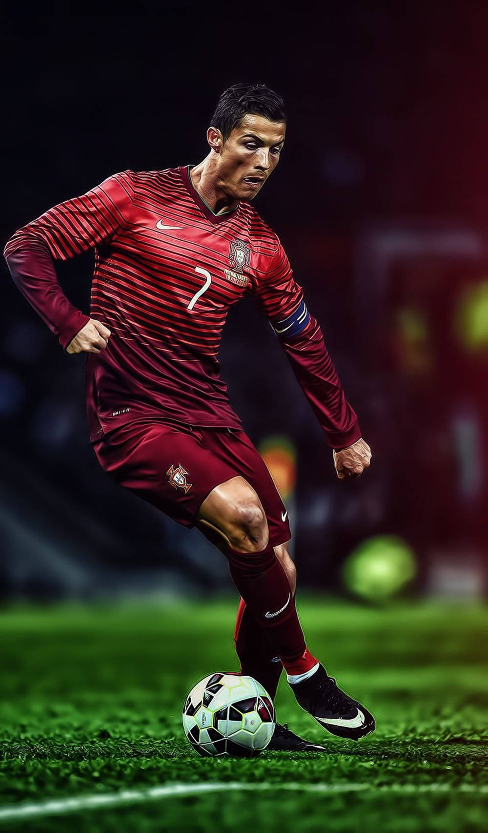 Cristiano Ronaldo 桌布 壁紙 — 基斯坦奴·朗拿度身穿紅色葡萄牙球衣，在球場燈光下於充滿活力的綠色草地上盤球。