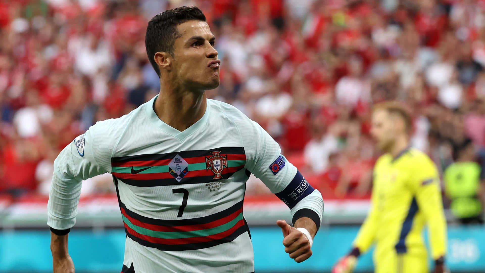 Ronaldo 桌布 壁紙 — 基斯坦奴·朗拿度身穿葡萄牙白色球衣，帶有紅綠條紋，在座無虛席的球場上豎起大拇指慶祝入球。