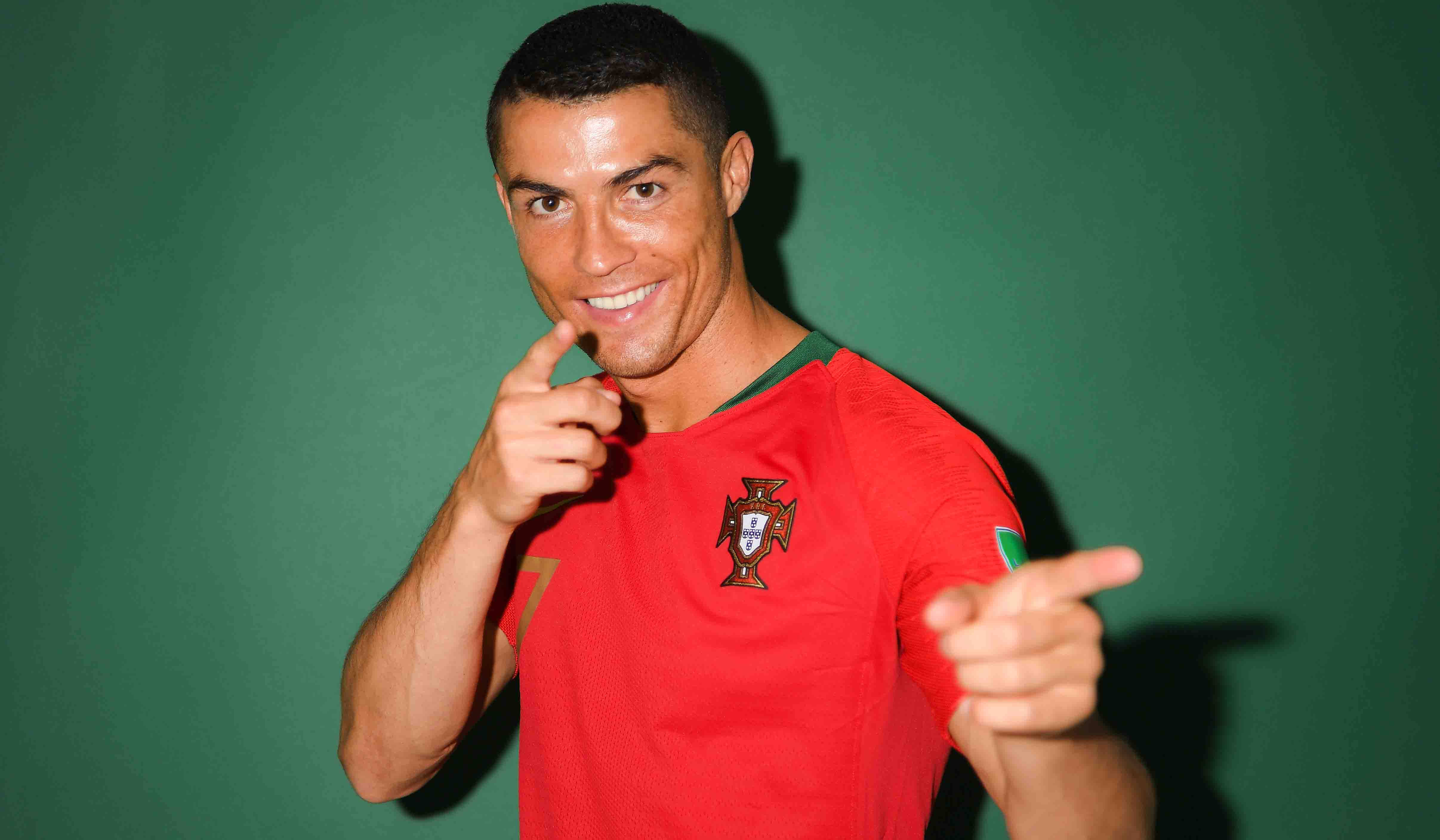 Cristiano Ronaldo 桌布 壁紙 — 基斯坦奴·朗拿度身穿葡萄牙紅色球衣，在純綠色背景下自信地指向鏡頭。