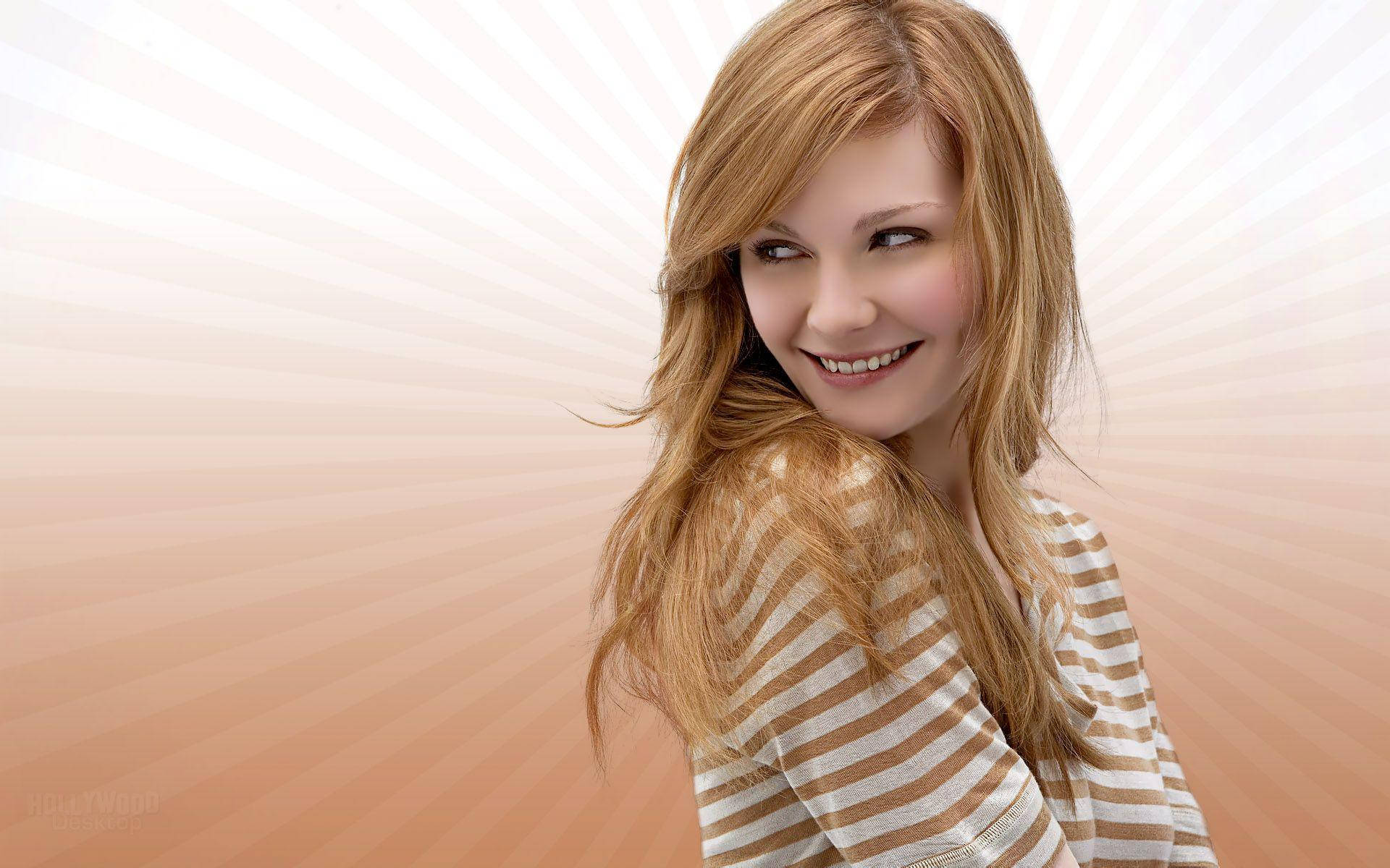 基斯汀·鄧斯特向量藝術 壁紙 — 一位微笑的長金髮女性穿著條紋襯衫，背景是耀眼的桃色和白色太陽光線。