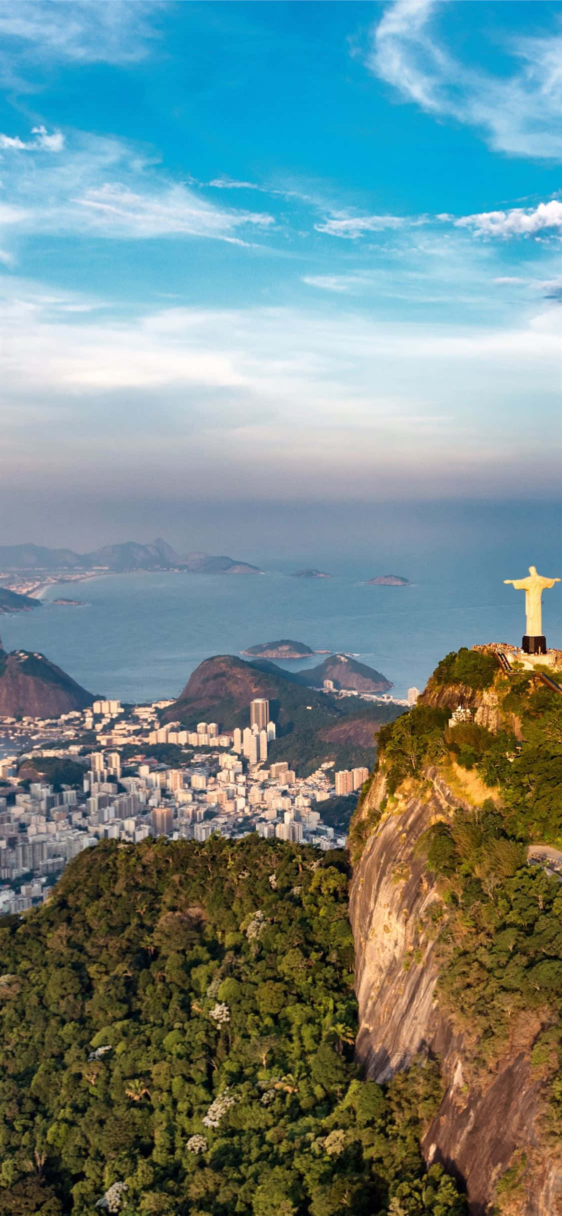 Brazil 桌布 壁紙 — 基督救世主雕像俯瞰里約熱內盧的城市景觀和海洋，天空湛藍，白雲點綴。