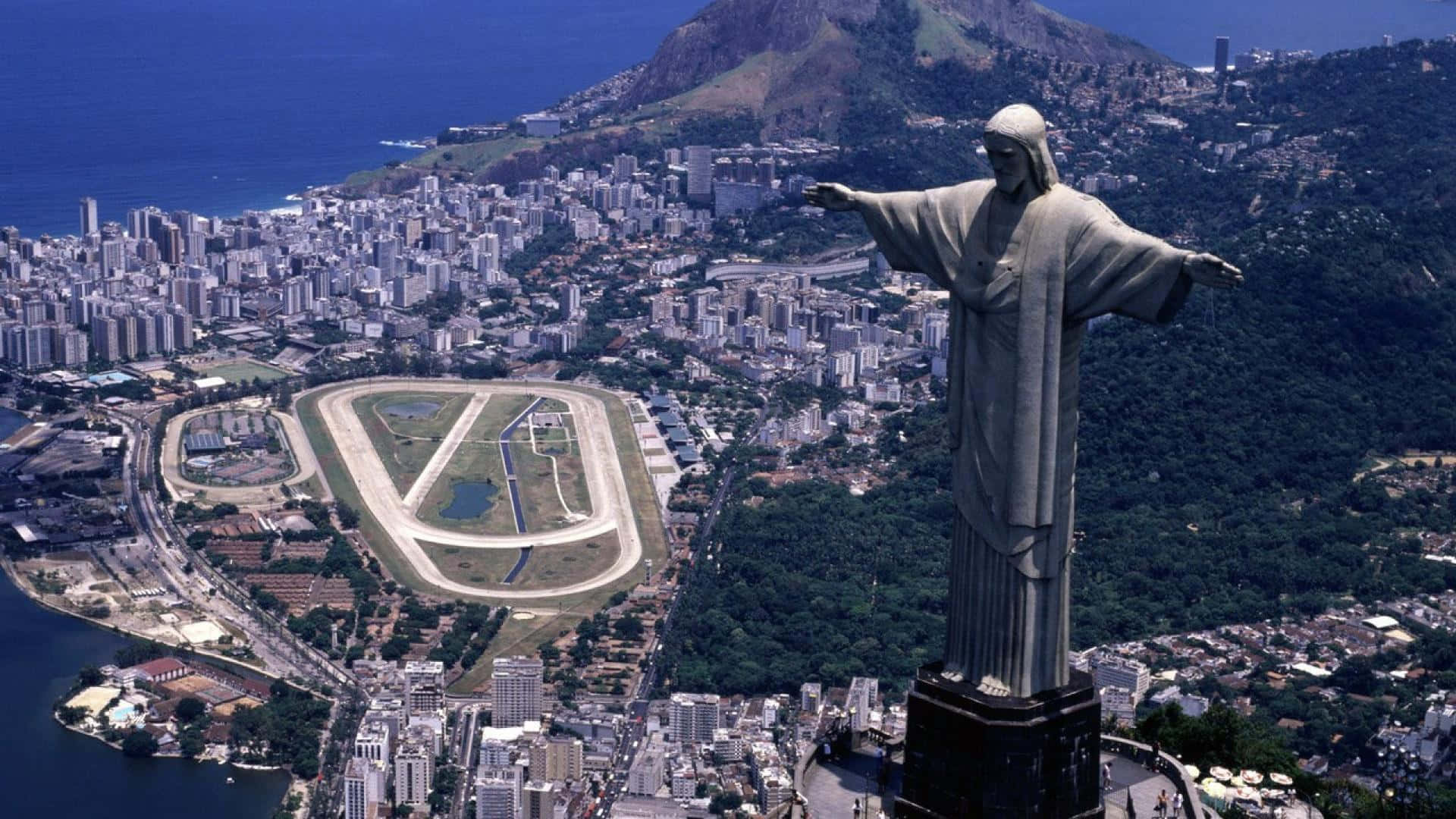Brazil 桌布 壁紙 — 基督救世主雕像俯瞰里約熱內盧的航拍圖，下方有賽車道和沿海城市景觀。