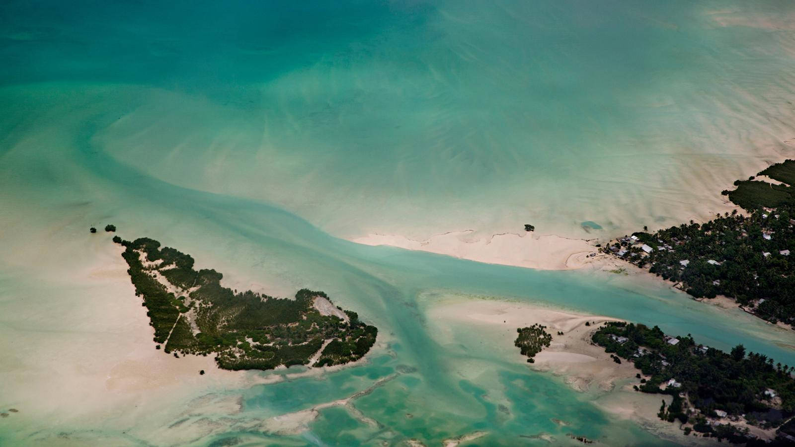 基里巴斯島嶼海景 壁紙 — 從高空俯瞰，碧綠的海水圍繞著沙質小島和茂密的綠色植被，零星分佈著建築物。