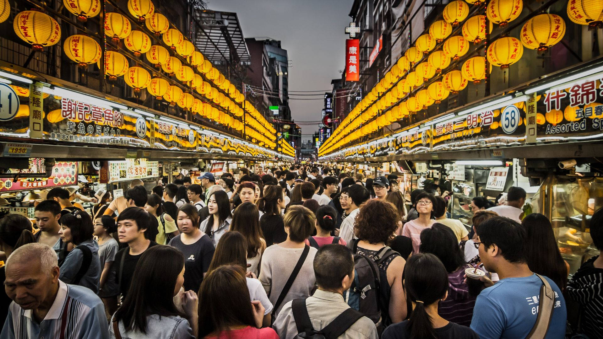 擁擠的夜市街道，有發光的燈籠和食物攤位。