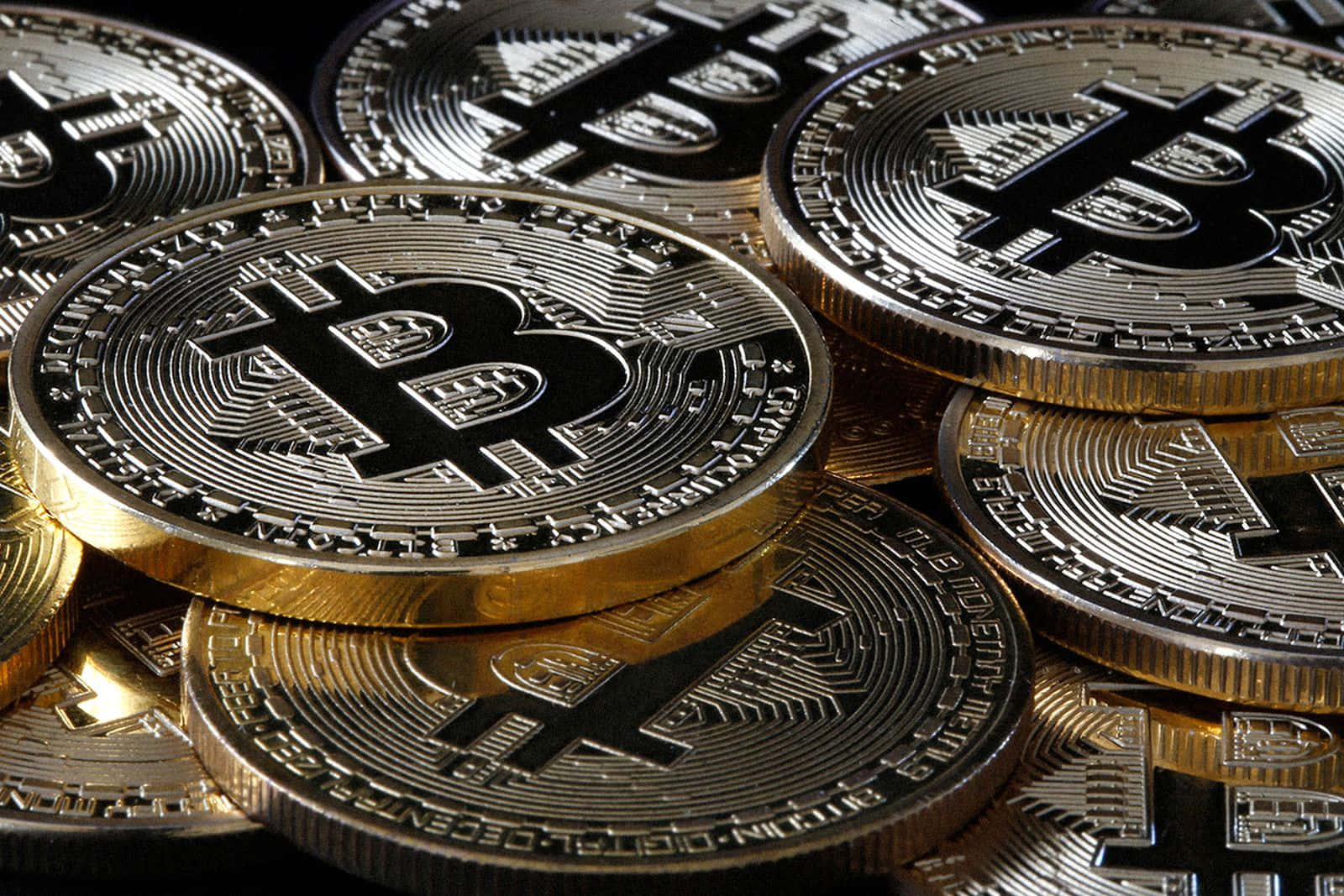 堆疊的金色和銀色比特幣硬幣，帶有雕刻符號。 — 比特幣 壁紙