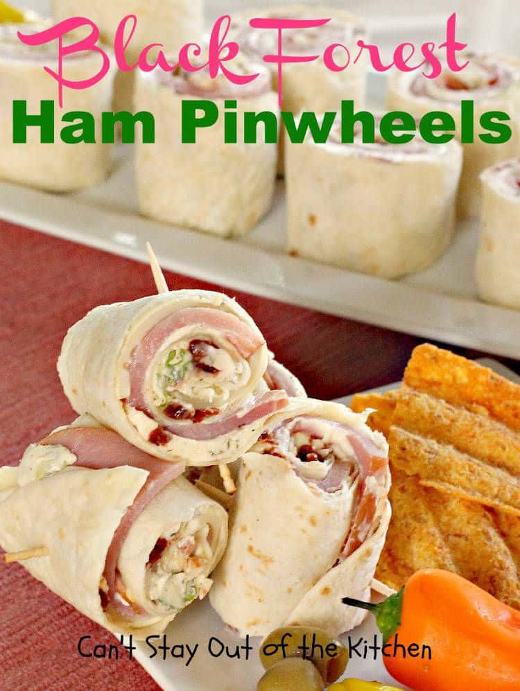 Black Forest Ham 桌布 壁紙 — 堆疊的黑森林火腿卷，內有奶油餡料和煙肉粒，旁邊放有墨西哥玉米片和一個辣椒，置於紅布上。