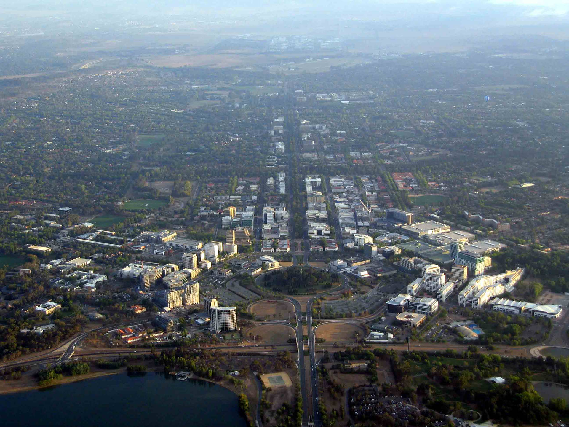 從高空俯瞰城市，有建築物、道路和綠地，在朦朧的日光下。