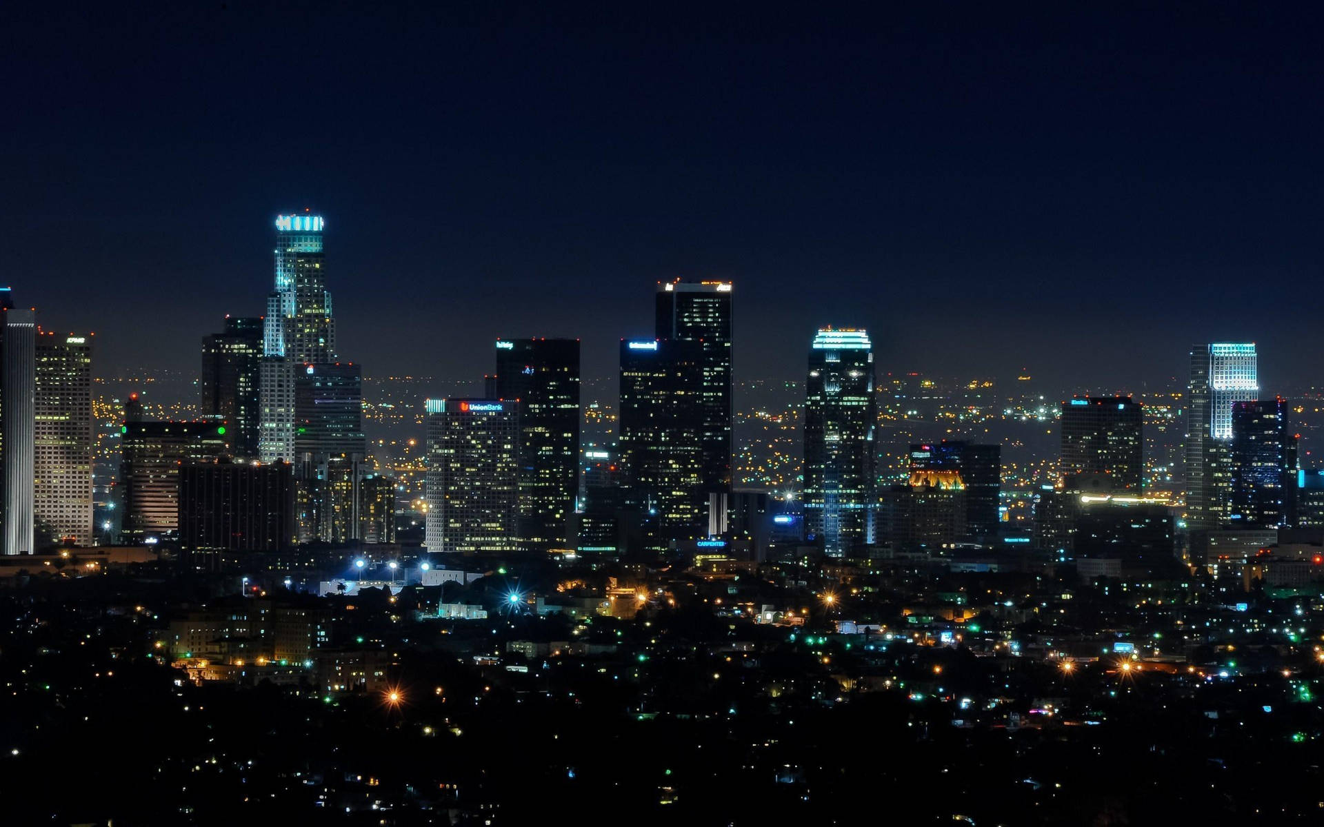 堪薩斯城午夜 壁紙 — 充滿活力的城市天際線全景夜景，高聳的摩天大樓在深藍色天空的映襯下閃耀。