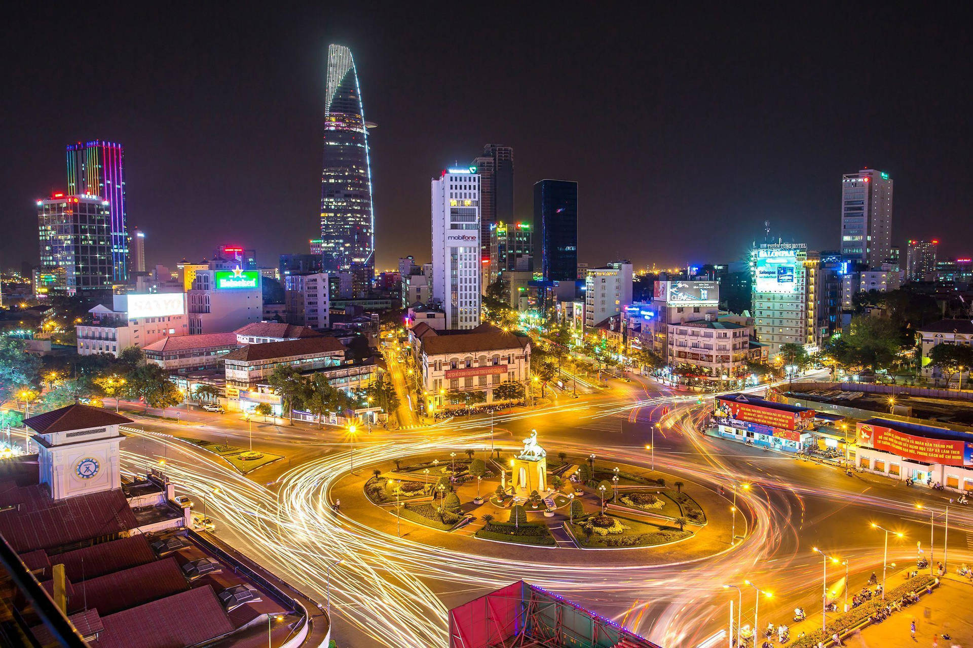 夜晚的城市，明亮的燈光和圍繞中央迴旋處移動的汽車軌跡。