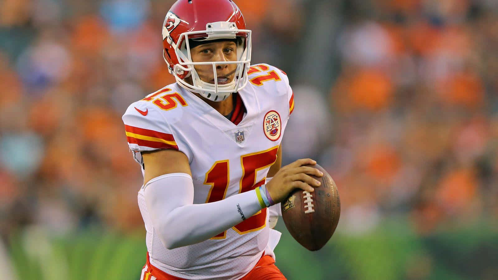 NFL四分衛穿著白色和紅色制服在比賽中拿著橄欖球。