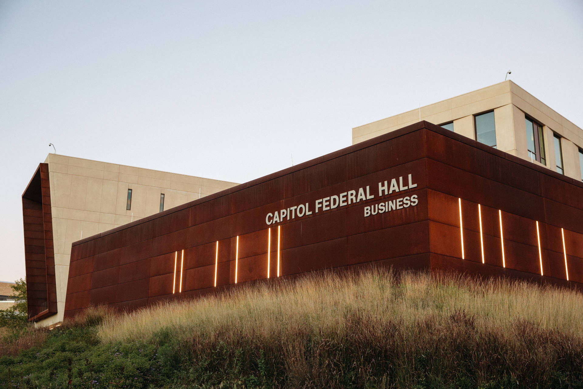 Capitol Federal Hall商業建築，帶有鏽色金屬面板和黃昏時發光的燈光。