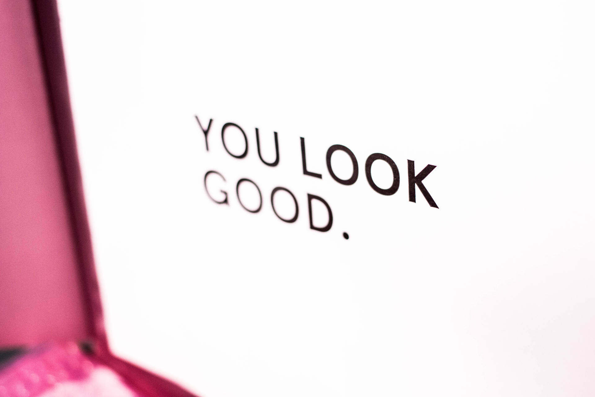 一張白色卡片，上面有粗體黑色字母的訊息「YOU LOOK GOOD」。