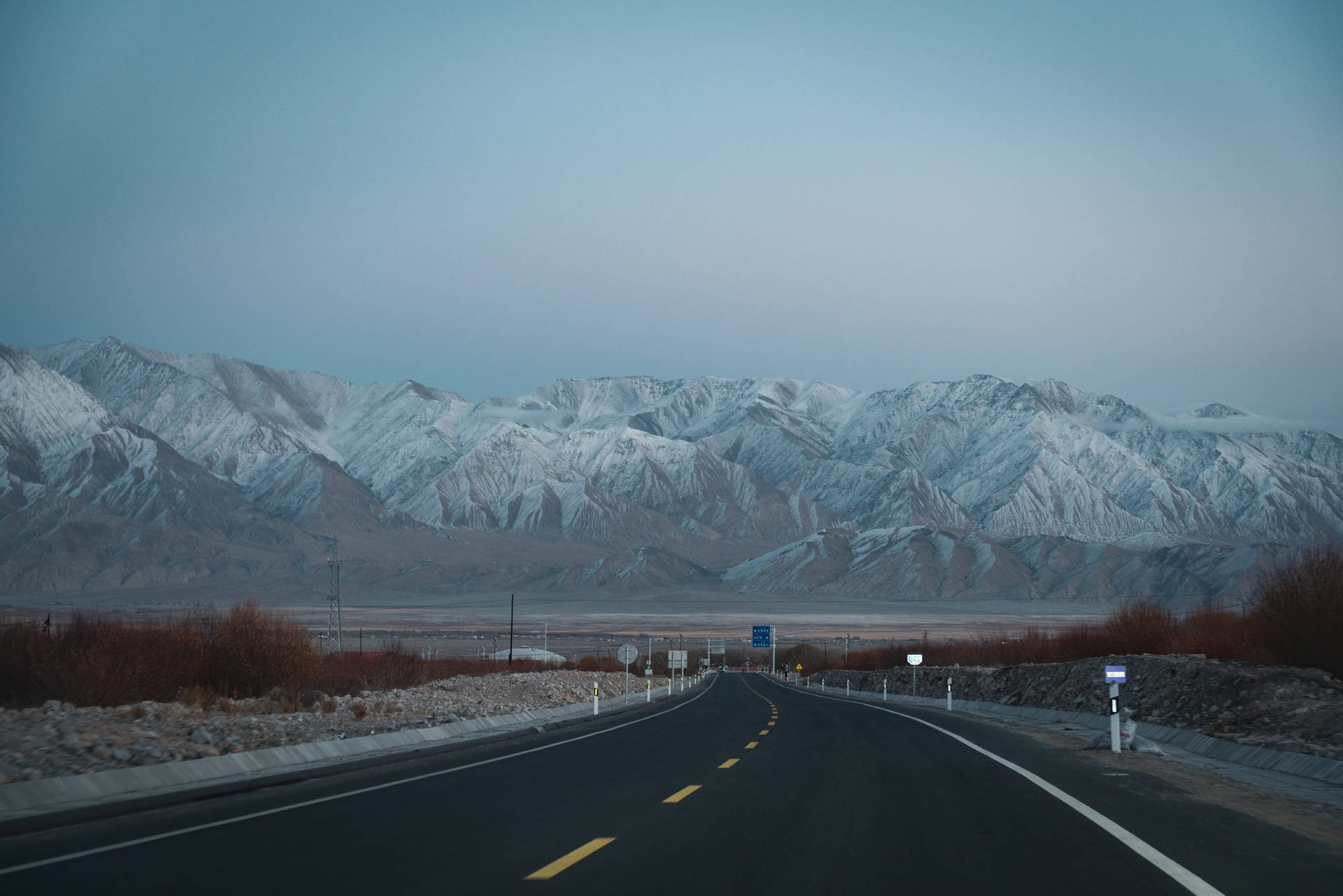 一條空蕩蕩的道路，在暮色中通向積雪的山峰。