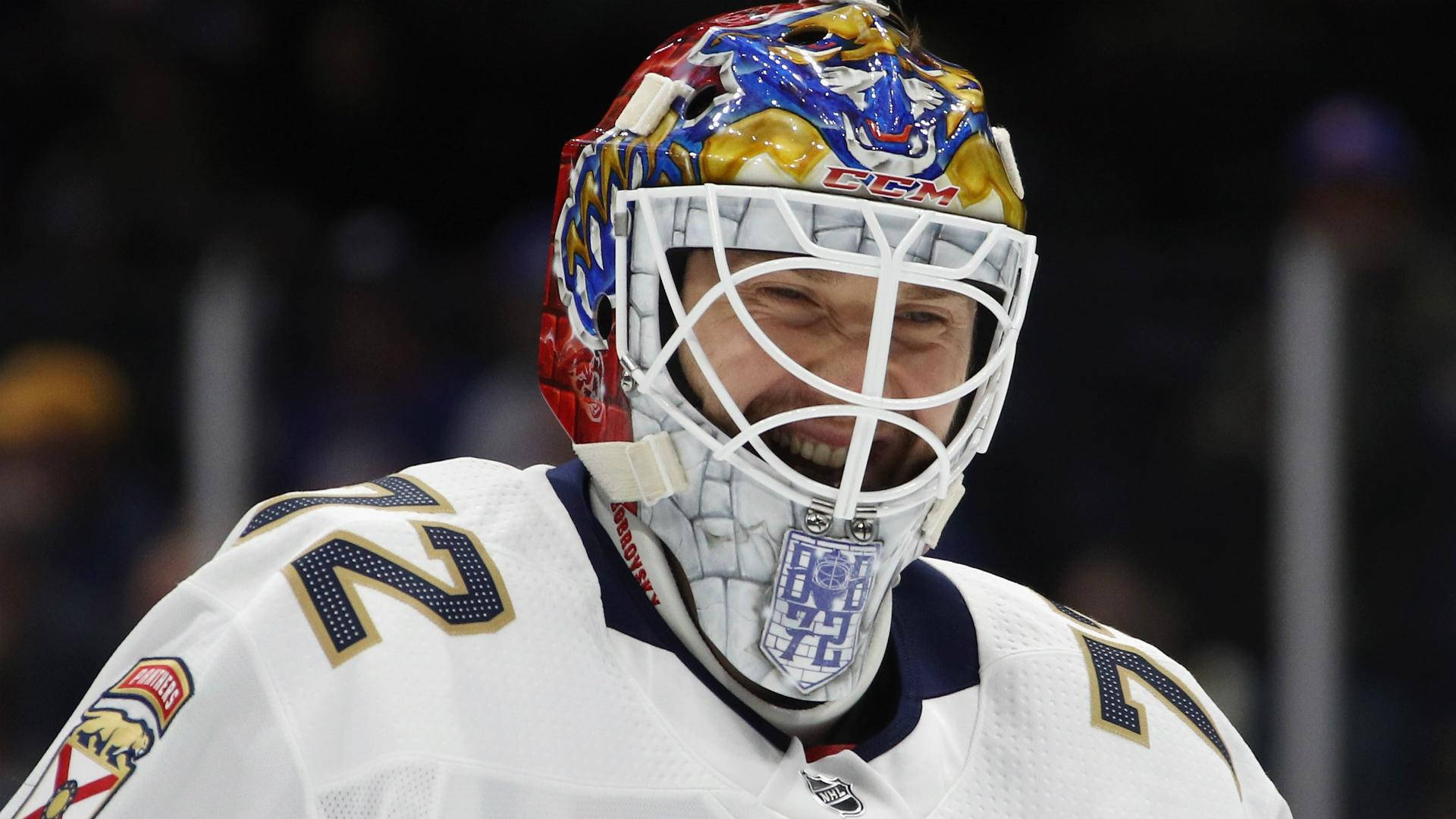 塞吉·博布羅夫斯基，NHL頂尖守門員動態表現 壁紙 — 一位身穿白色球衣、背號2的冰球守門員，戴著彩色頭盔和面罩，露出燦爛的笑容。