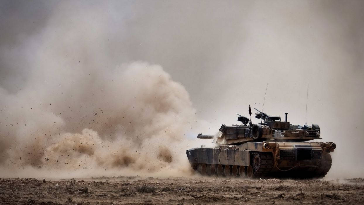 軍用坦克在塵土飛揚的沙漠地形中快速移動。