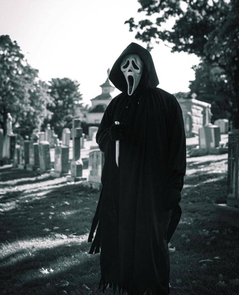 Ghostface在墓園中於明亮陽光下持刀。