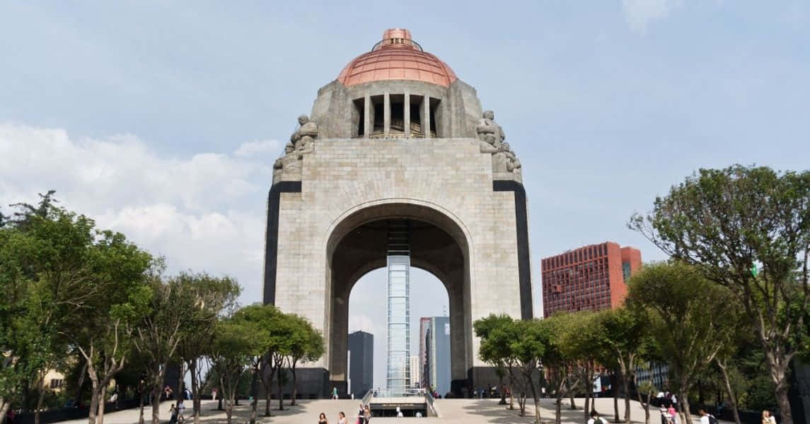 大型石造紀念碑，頂部有銅製圓頂，被樹木和城市建築包圍。