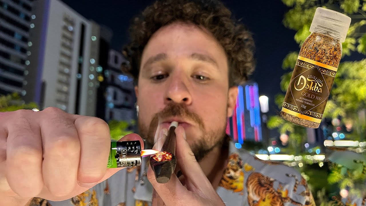 男人在夜晚的城市中點燃大麻煙，有霓虹燈和一個漂浮的香料瓶。