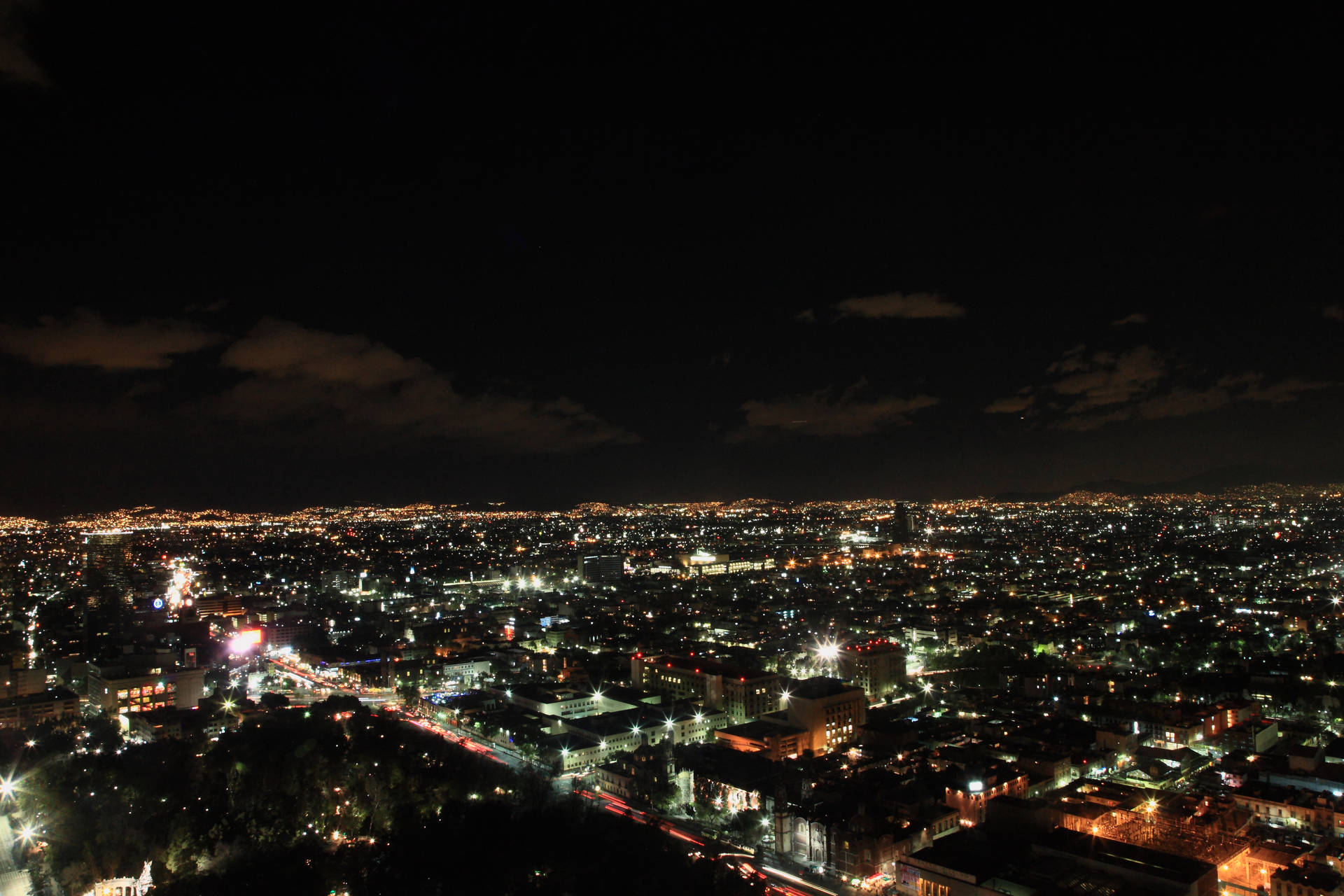多雲天空下，密集燈光的城市夜景，街道和建築物閃閃發光。
