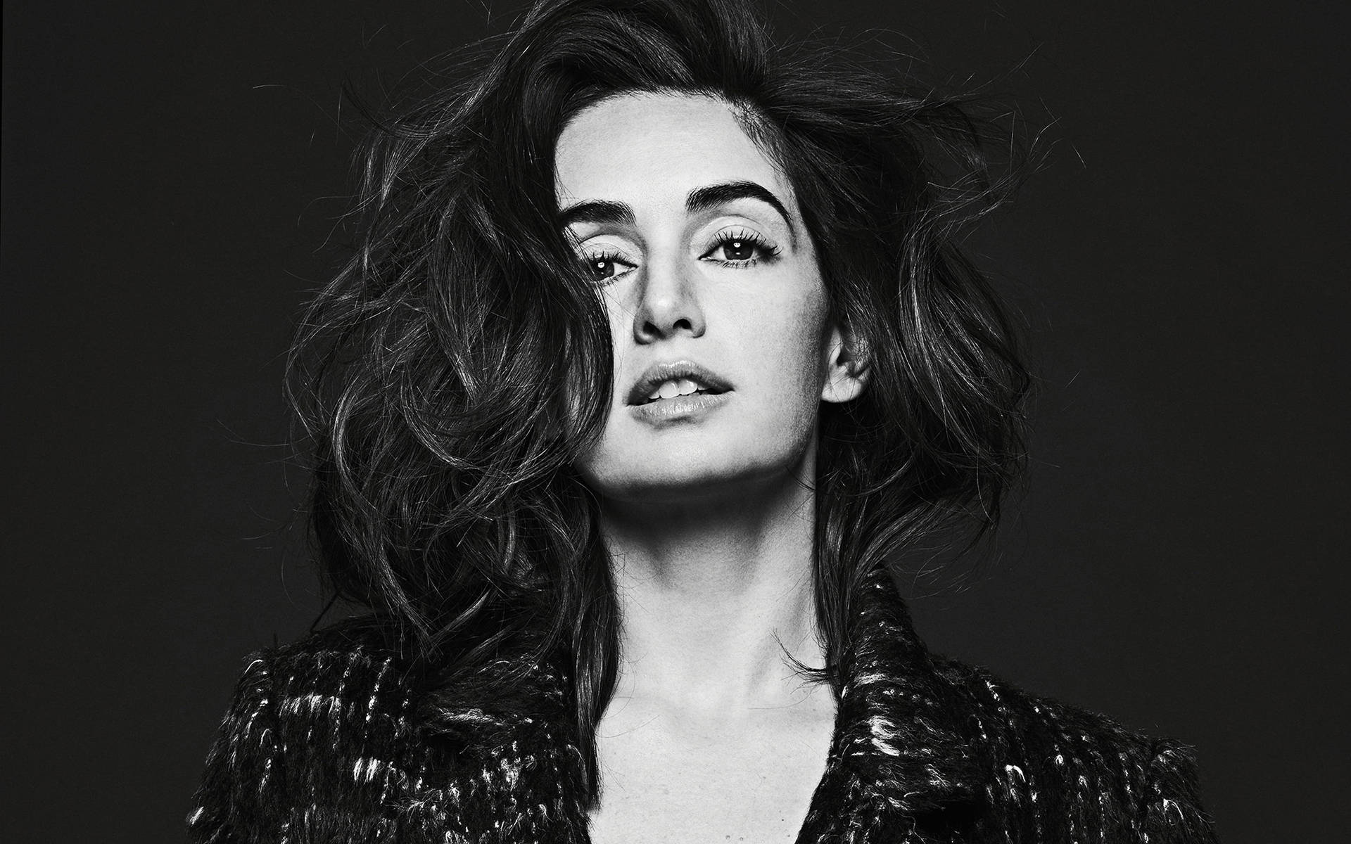 一位頭髮凌亂的女性在黑白工作室肖像中向上看。