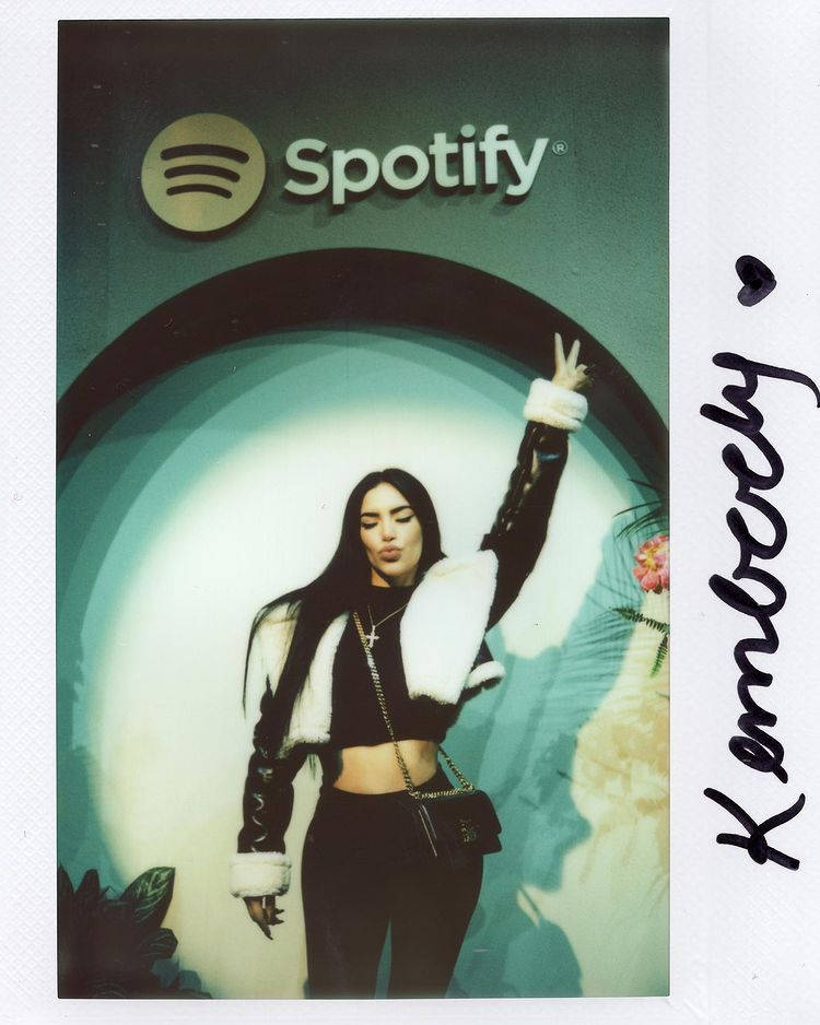 穿著時尚黑白服裝的女性在Spotify標誌下比出和平手勢。