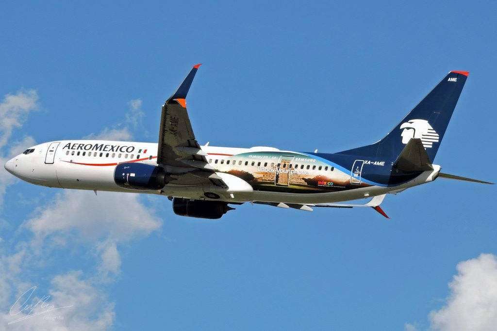 Aeromexico 客機在晴朗的藍天中飛行，天空中有零星雲朵。