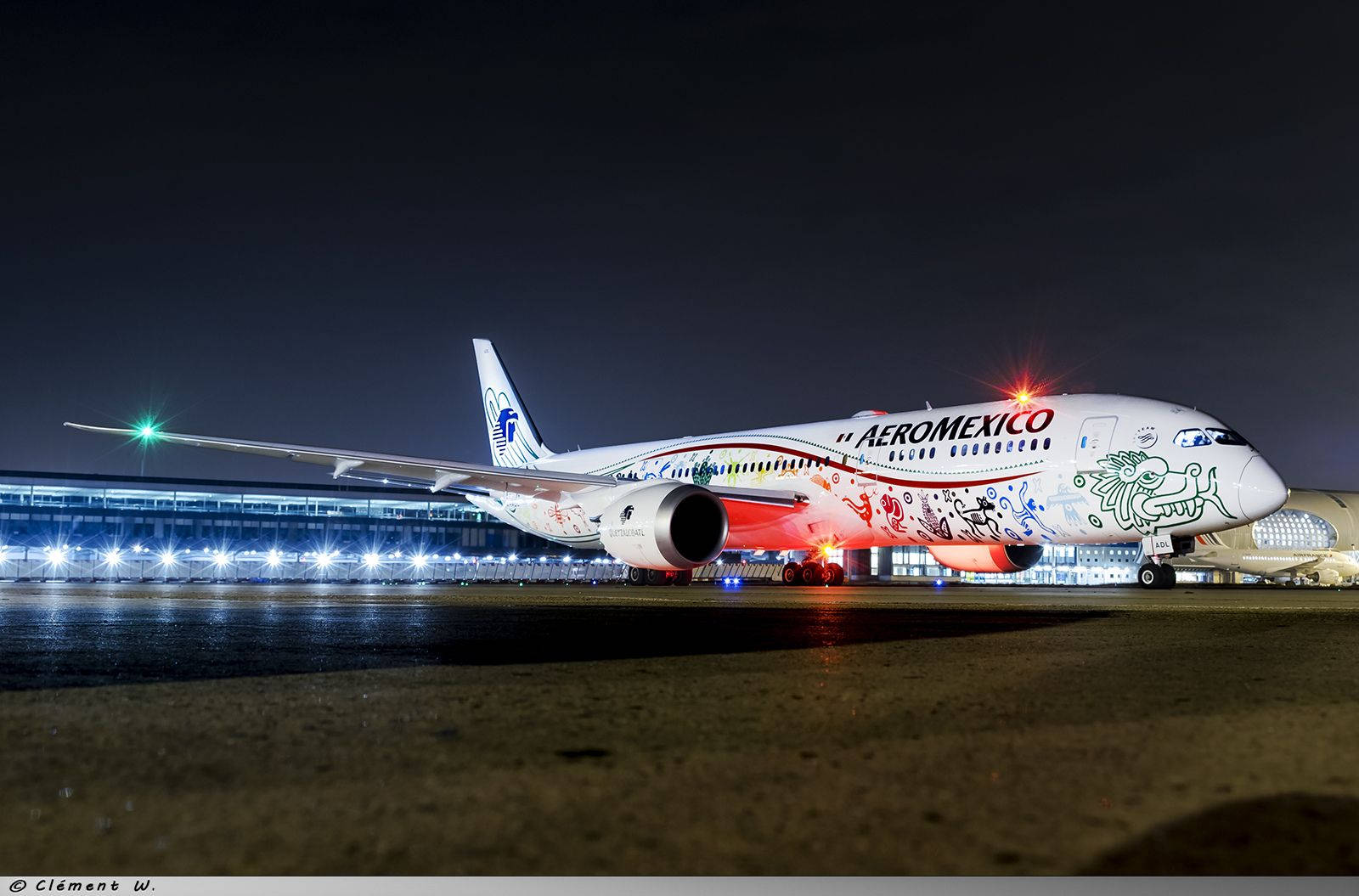 帶有文化藝術品的墨西哥航空飛機停在夜間機場客運大樓。