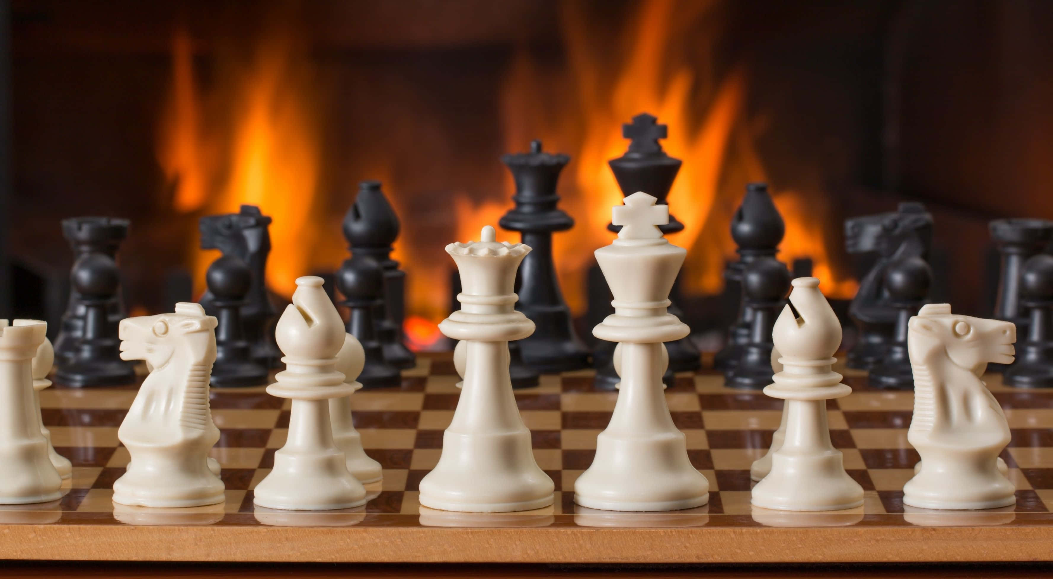 壁爐前木製棋盤上的國際象棋棋子 壁紙
