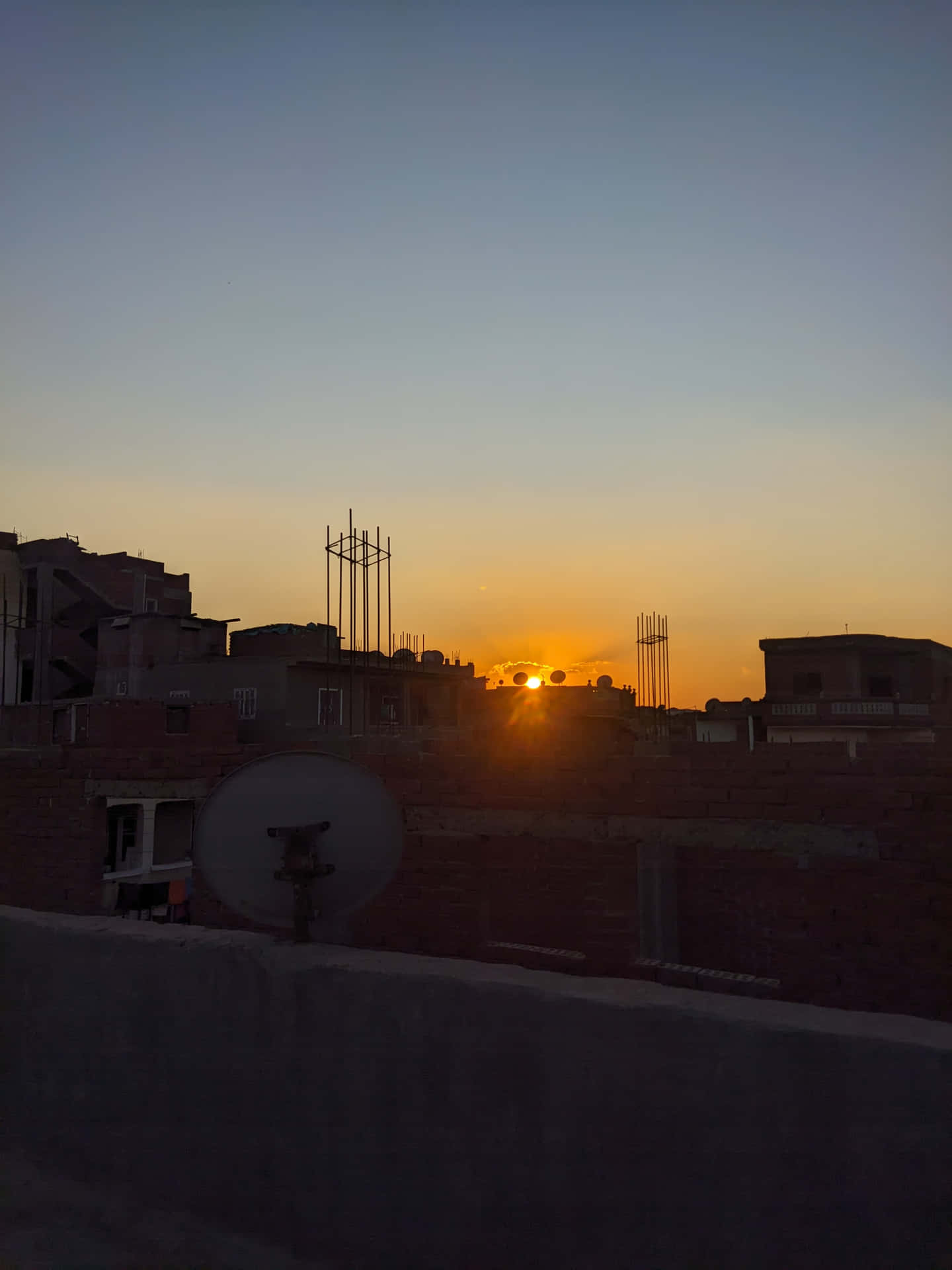 夕陽下的都市屋頂，帶有衛星天線和建築剪影