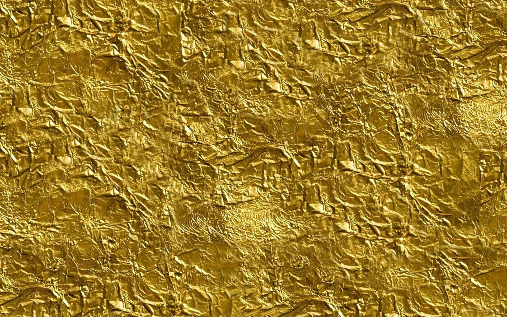 壓皺金箔高解析度紋理 壁紙 — 皺紋金箔的特寫，帶有複雜的摺痕和反射光線的高光。