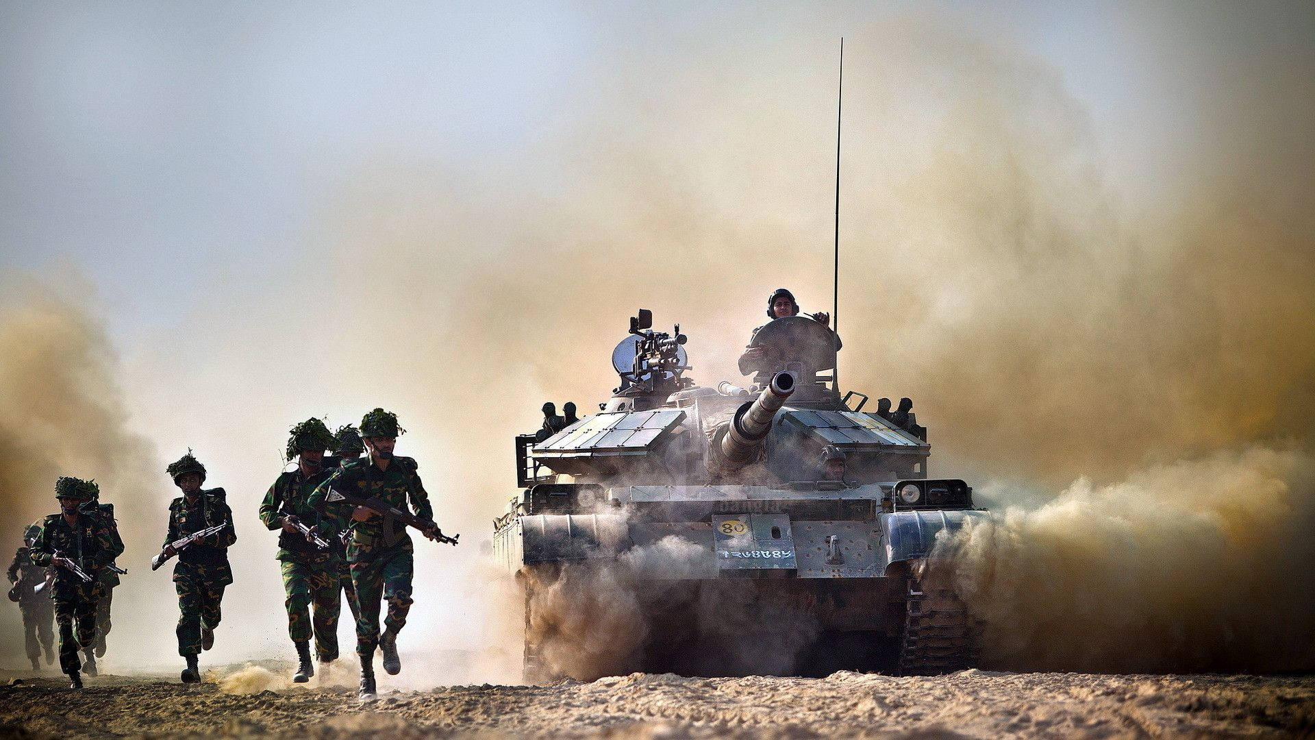白天，士兵在塵土飛揚的沙漠戰場上與坦克並肩奔跑。 — 軍事動圖 壁紙