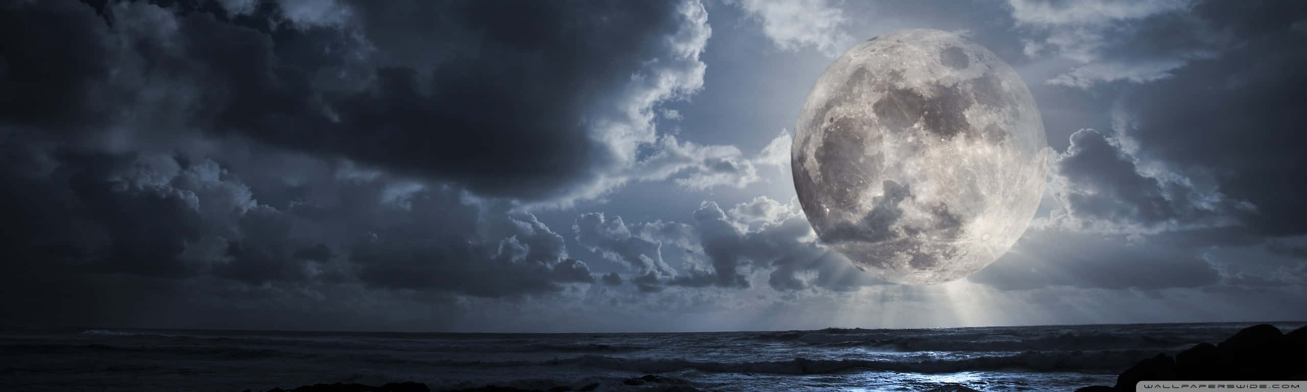 滿月在夜晚的暴風雨海洋上升起，伴隨著烏雲。