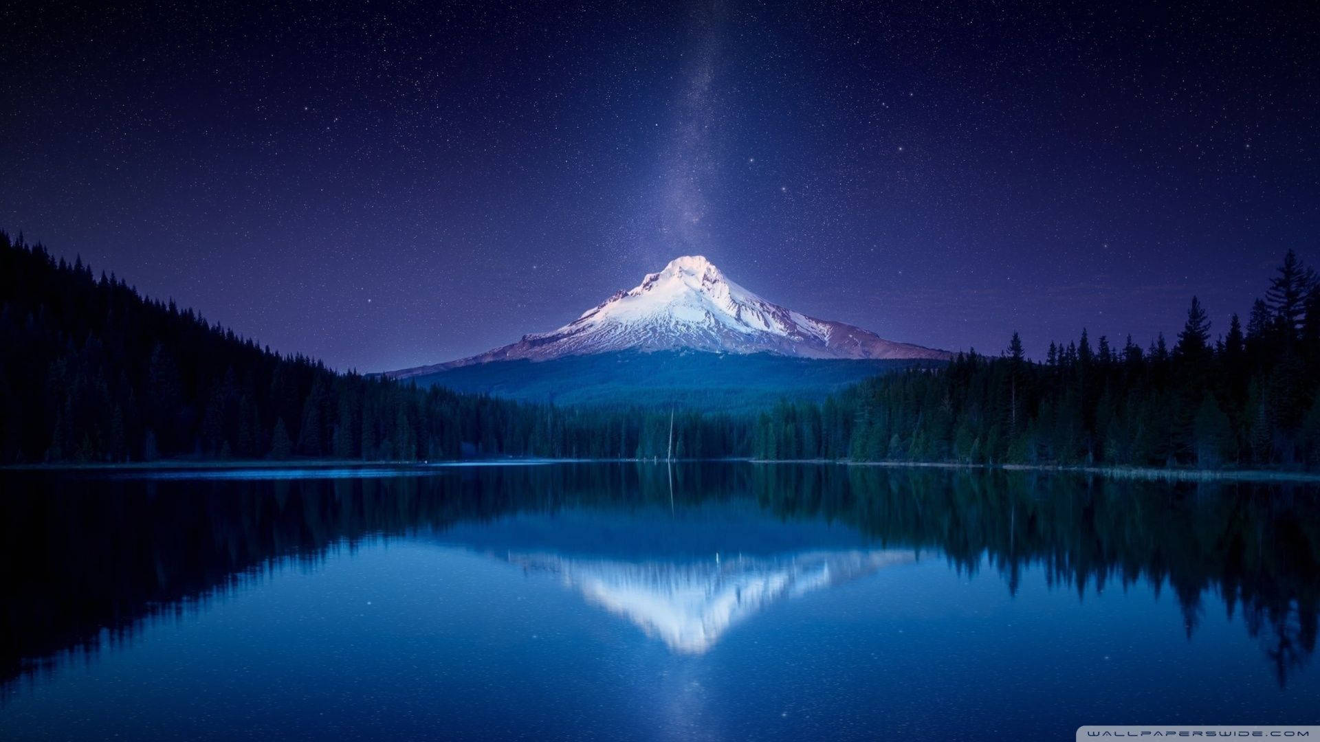 在繁星點點的夜空下，寧靜的湖泊中倒映著白雪覆蓋的山峰。