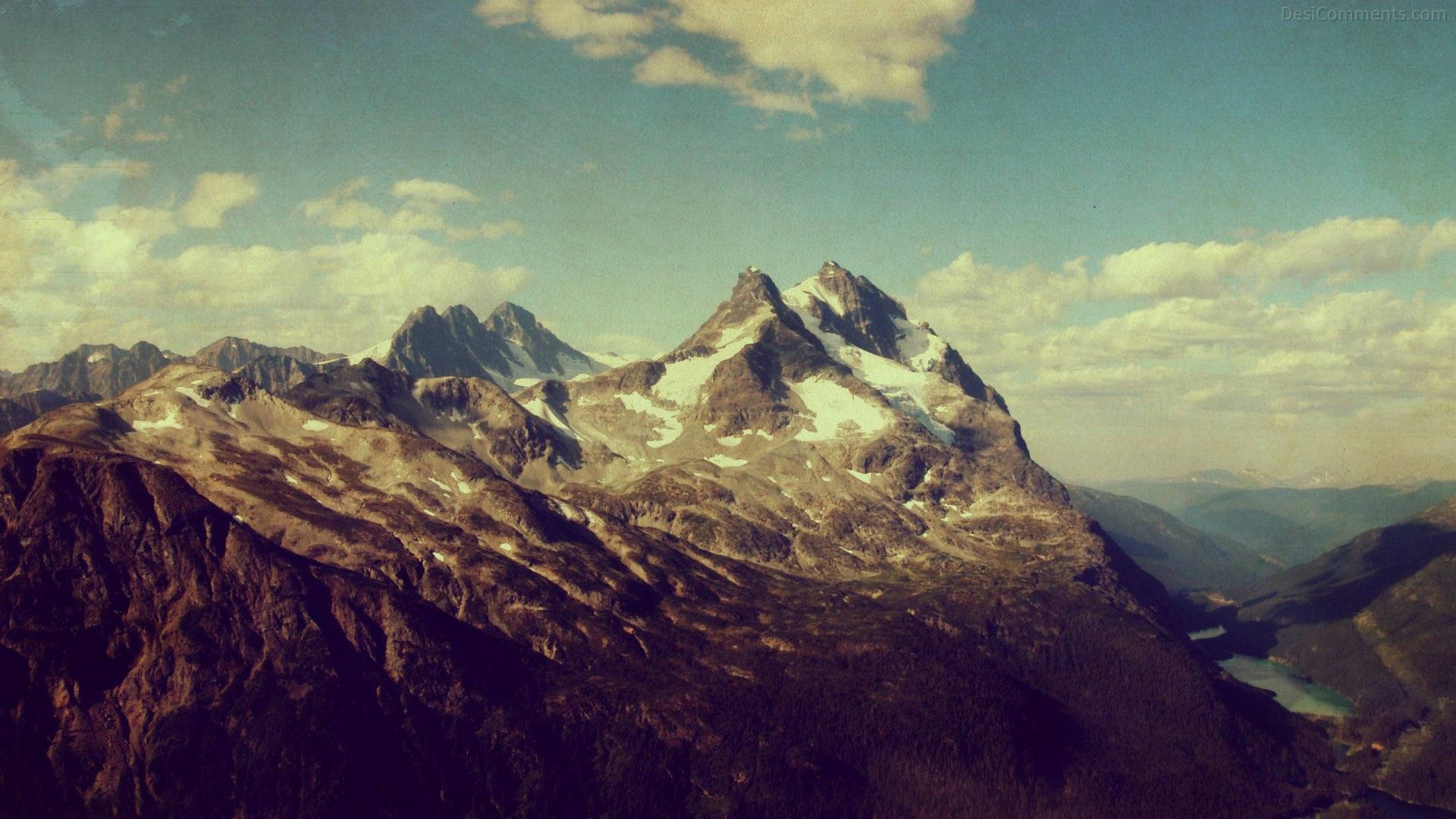 多雲天空下，山谷中的湖泊與雪山。